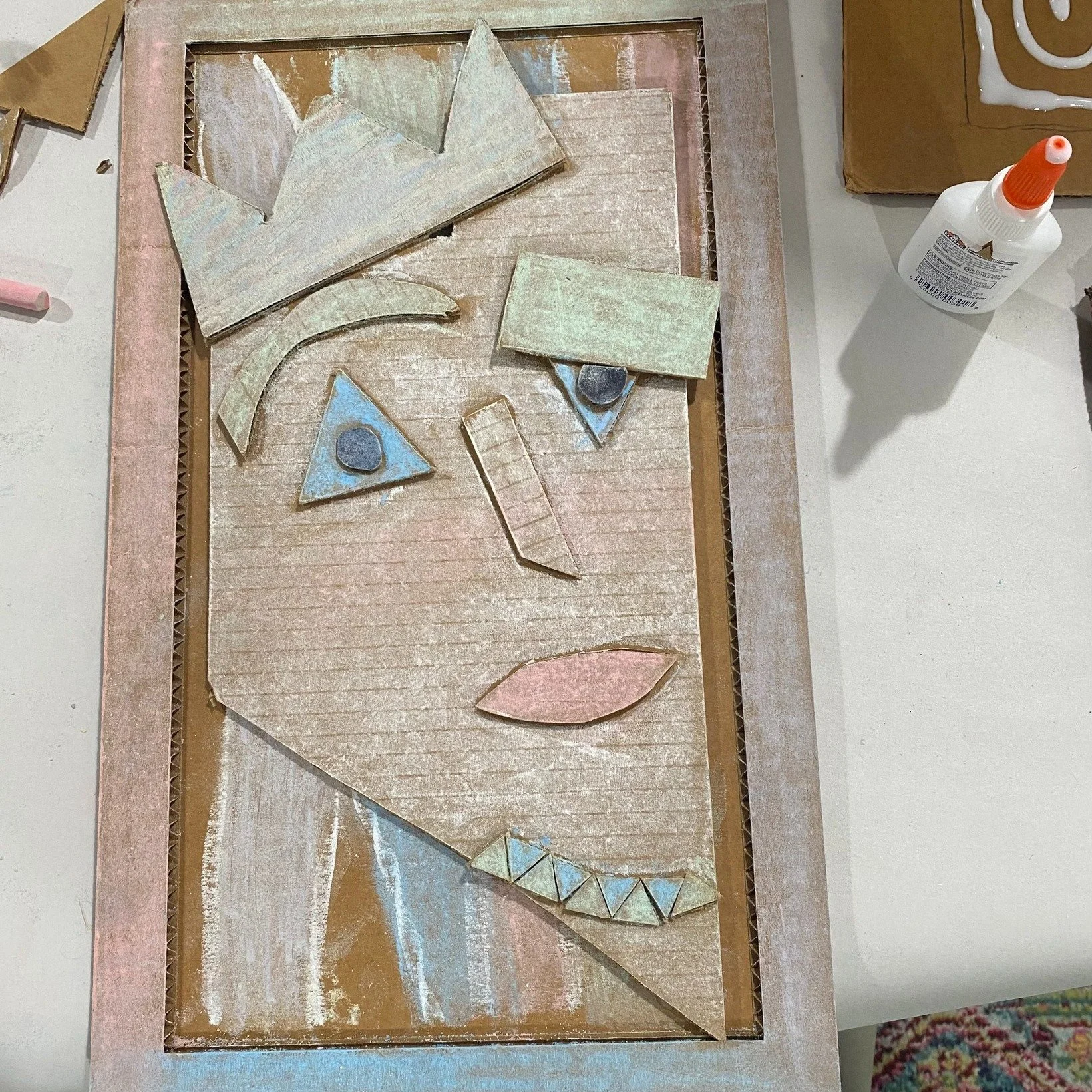 photograph of a student's picasso-like face using recycled cardboard pieces, chalk, and glue, as a result of a workshop at Frame Gallery Gifts & Art in Sewanee, Tennessee.