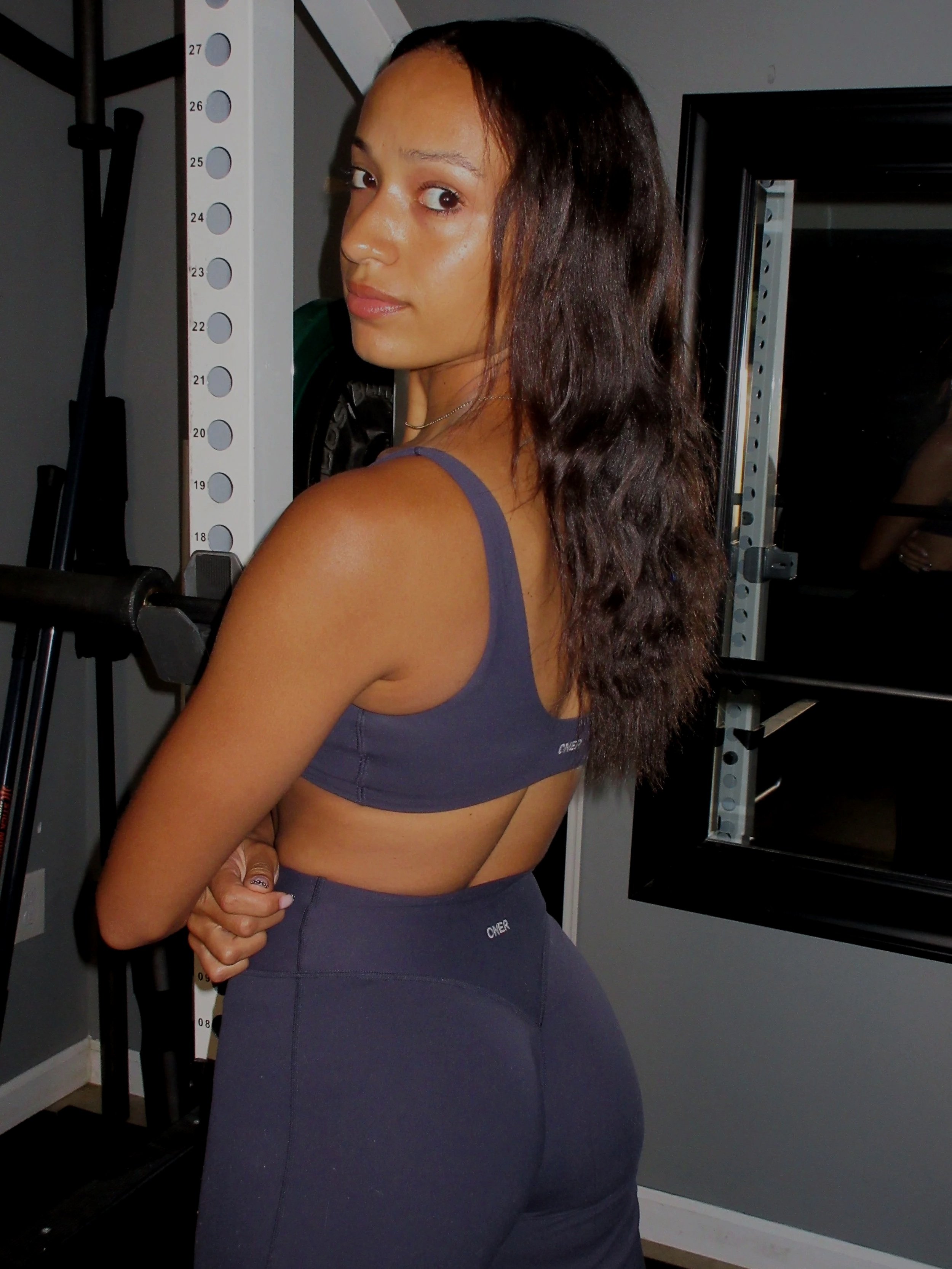 A woman in athletic wear standing next to a height chart in a gym or fitness studio.