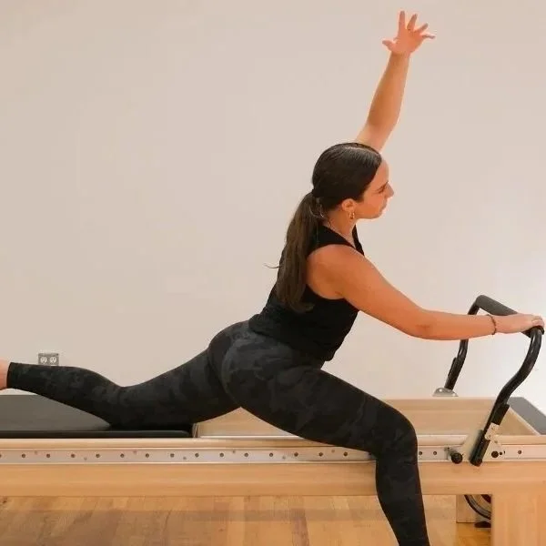 Client performing a controlled lunge on a reformer to build strength safely with osteoporosis