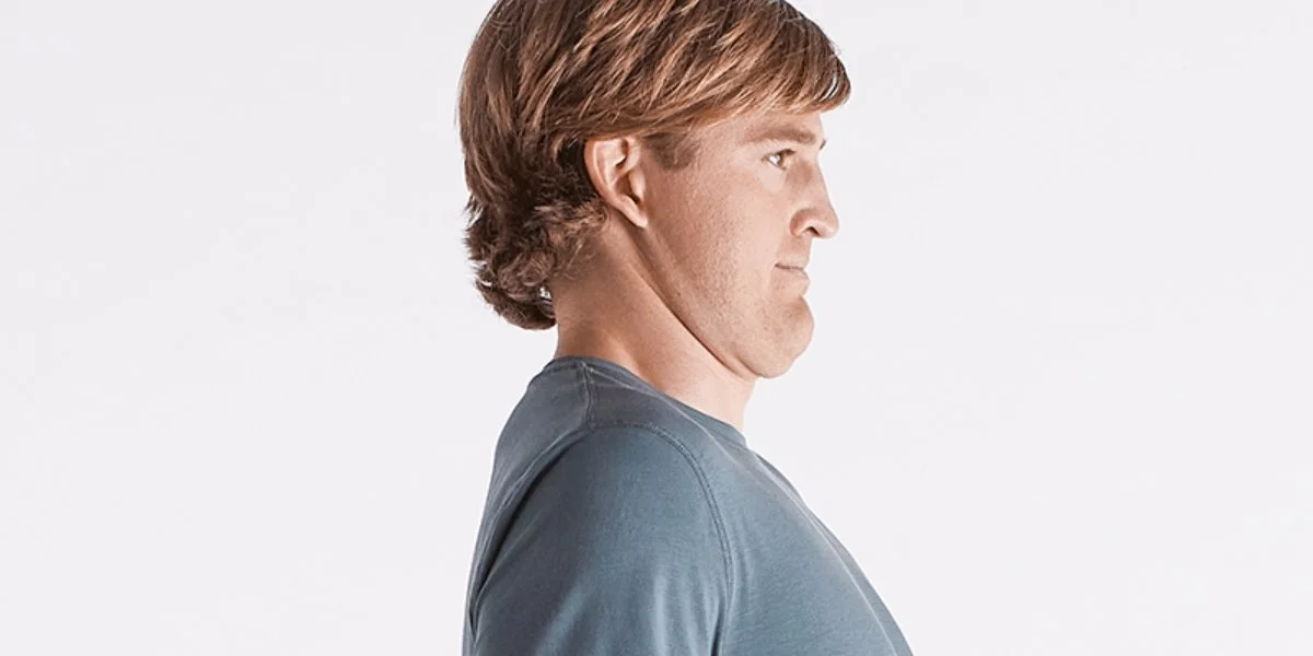Man demonstrating proper head posture in profile view, showing correct alignment for chin tucks exercise to strengthen neck muscles and improve cervical spine positioning