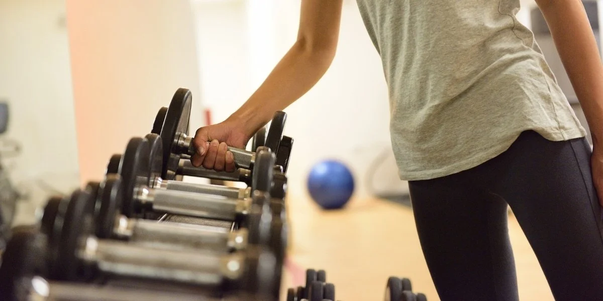 Person lifting dumbbells at a gym, demonstrating how to build functional strength through controlled resistance training.