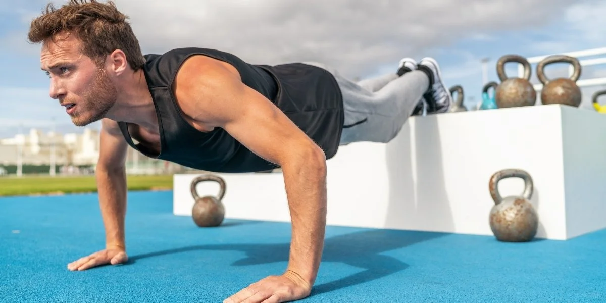 Athlete performing an elevated push-up outdoors, showing how to build functional strength using bodyweight exercises and core stability.