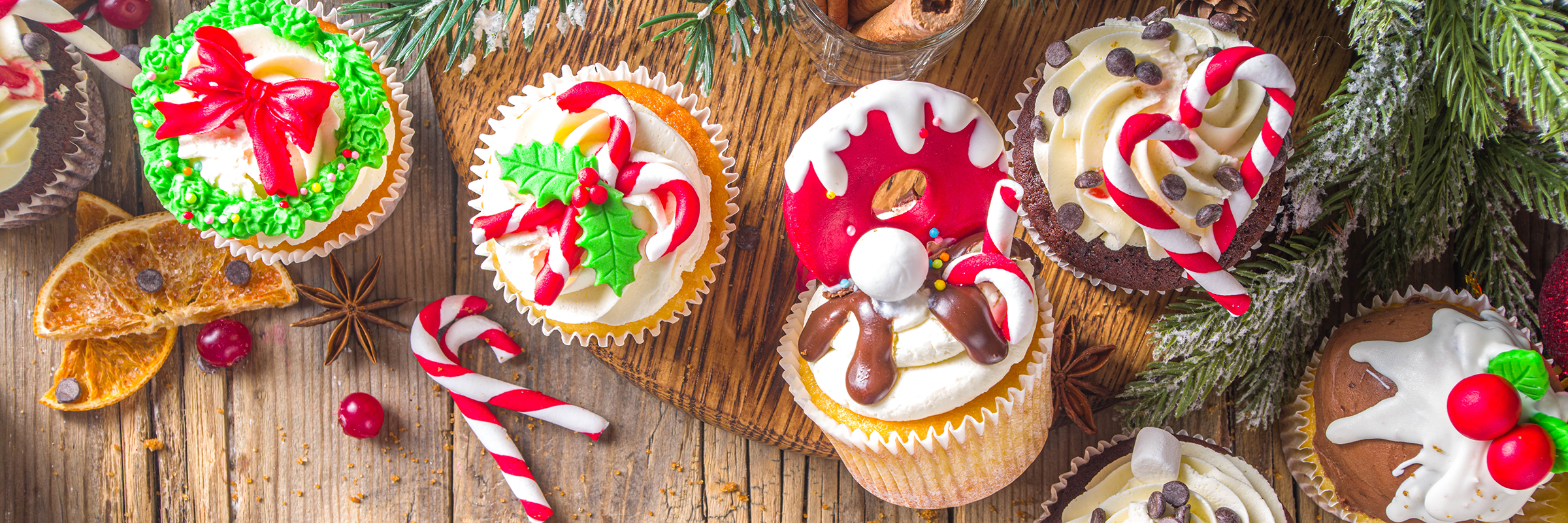 funny-christmas-cupcakes-homemade-sweet-cupcakes-with-sugar-glaze-form-christmas-decoration-symbols-wooden-background-with-xmas-decor_2400.png