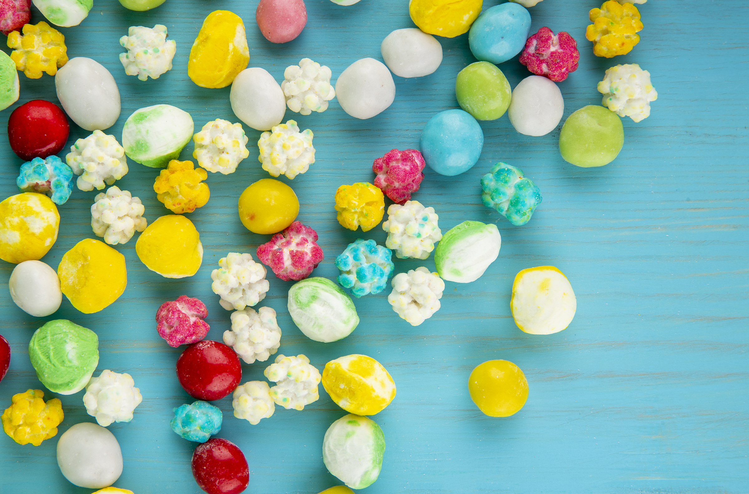 top-view-colorful-sweet-sugar-candies-scattered-blue-wooden-background_2400.png