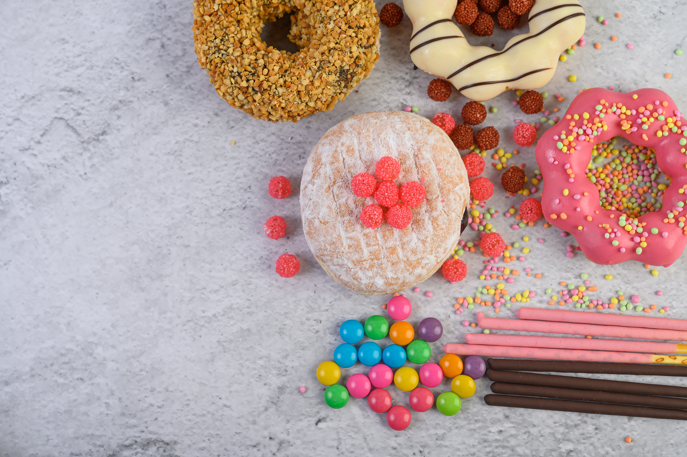 donuts-decorated-icing-sprinkles-white-surface-top-view_2400.png