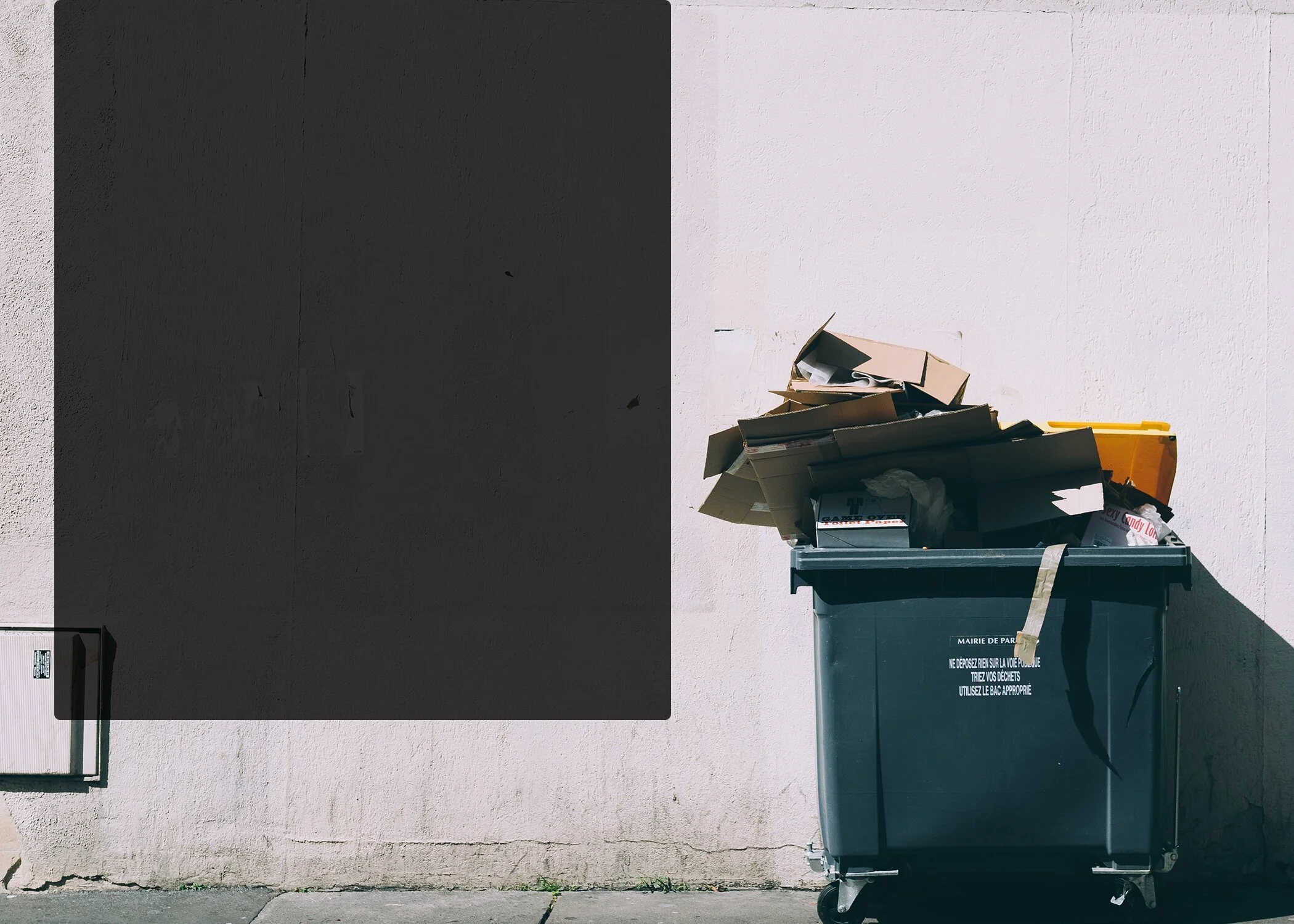 Outdoor waste bin filled with cardboard and discarded materials