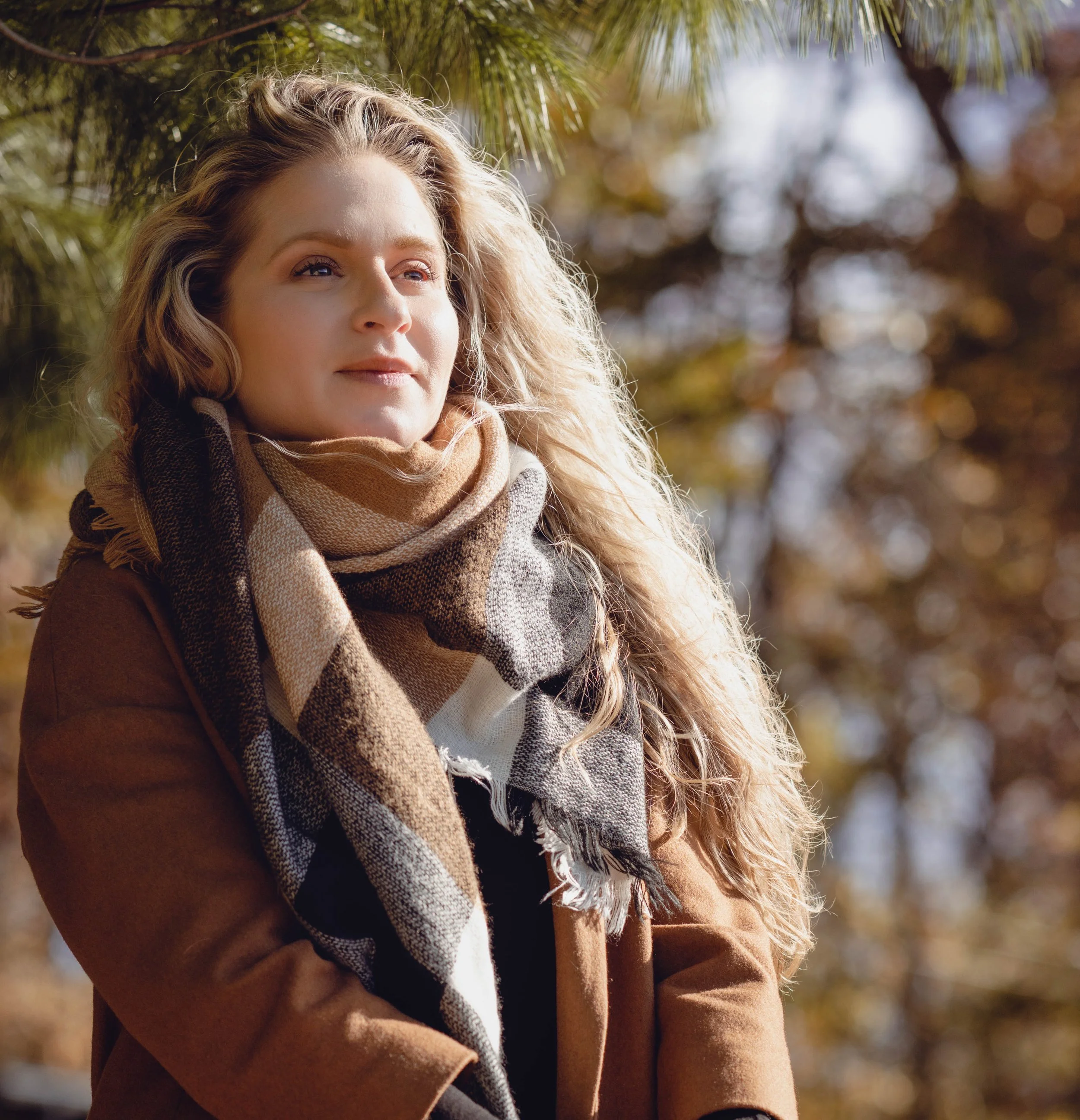 Woman standing in front of fall foliage.