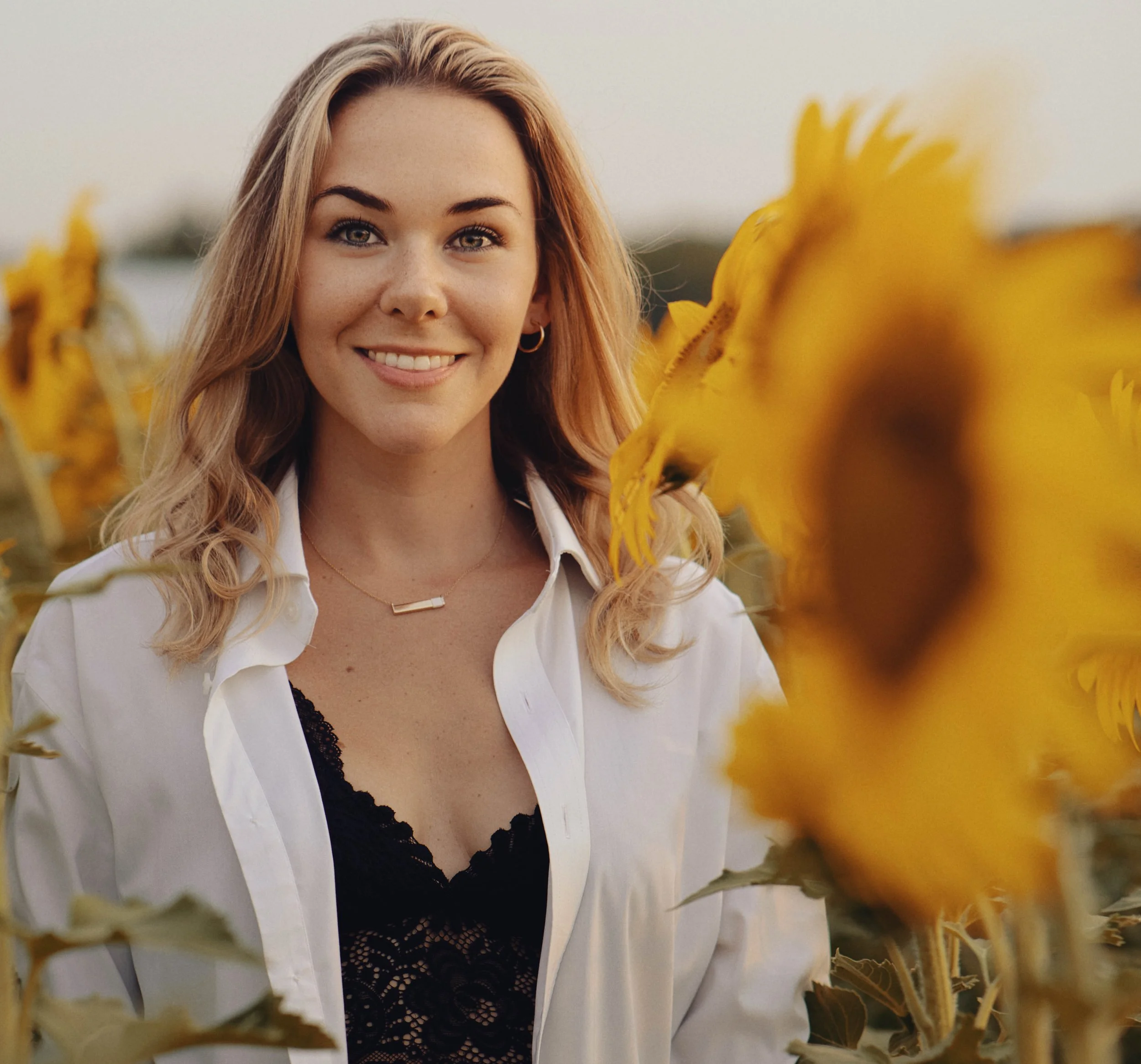 Woman in a sunflower field wearing a button up.