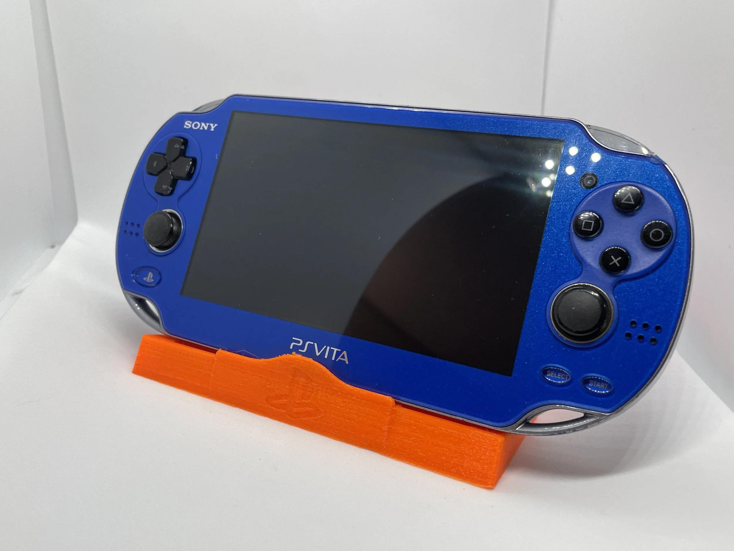 A blue Sony PlayStation Vita handheld gaming console resting on an orange stand.