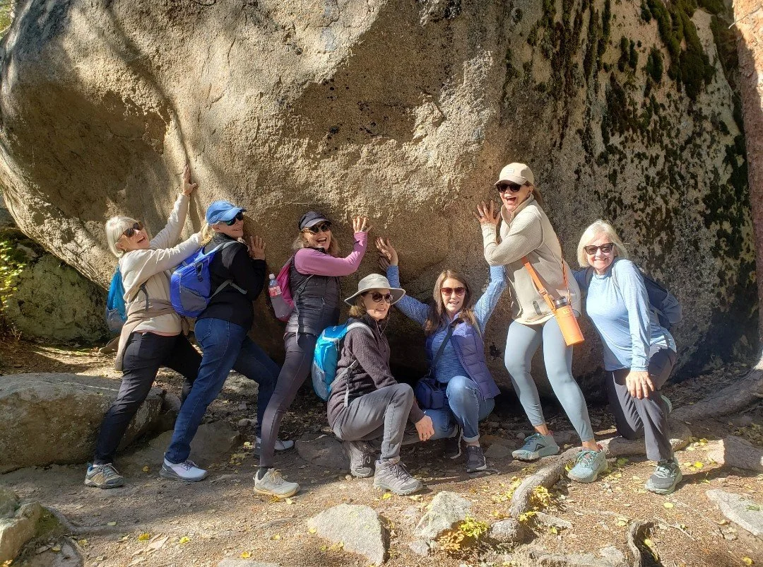 Group of ladies pose in front of a rock in Rocky Mountain National Park