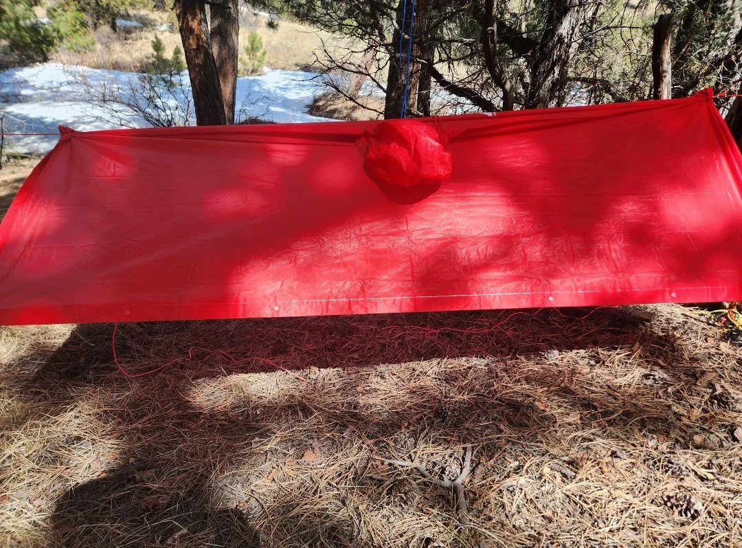 A shelter built from a rain poncho during a team building event with Femme Trek
