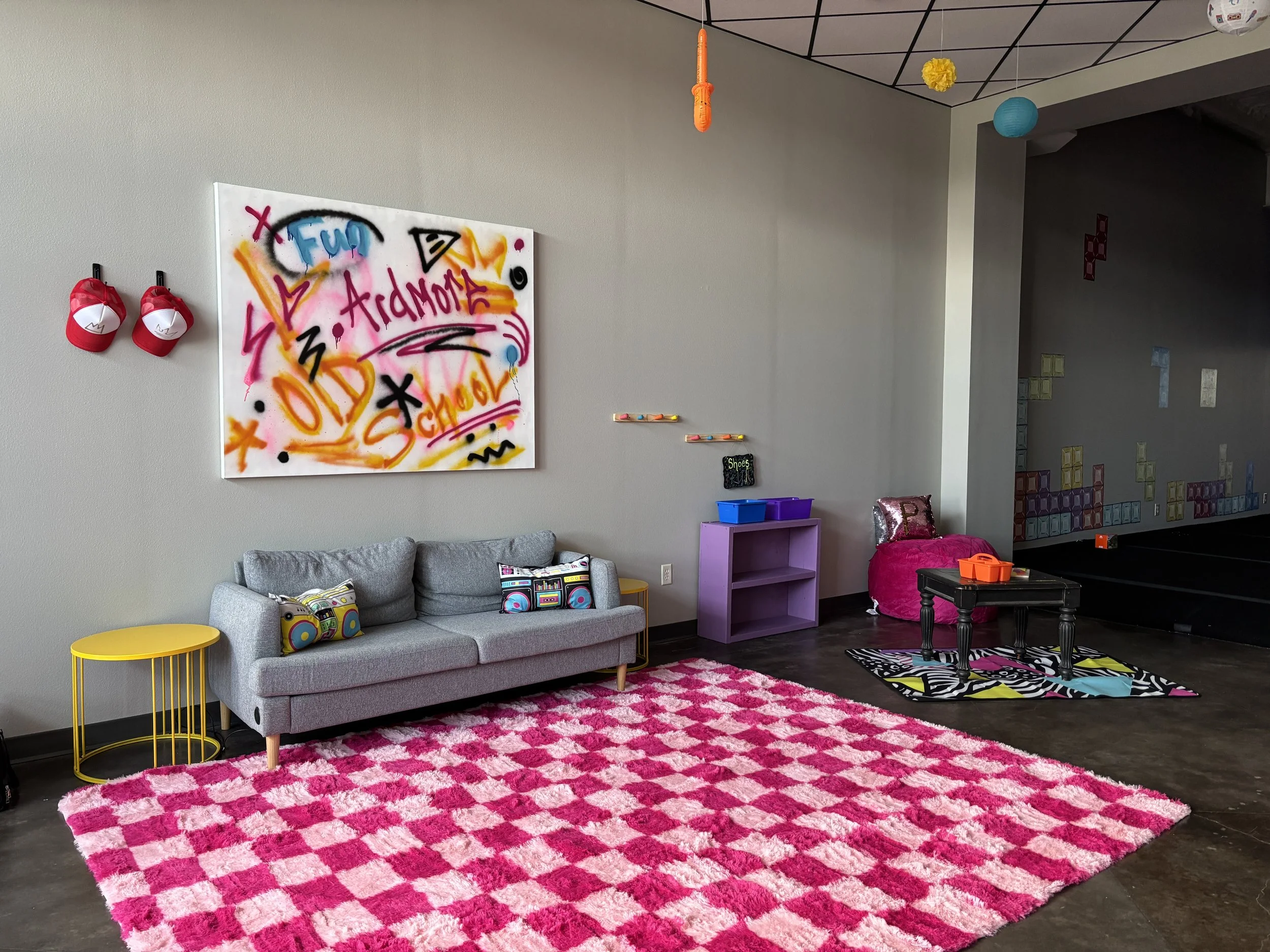 Checkered rug in large room with spray painted art on the wall. 