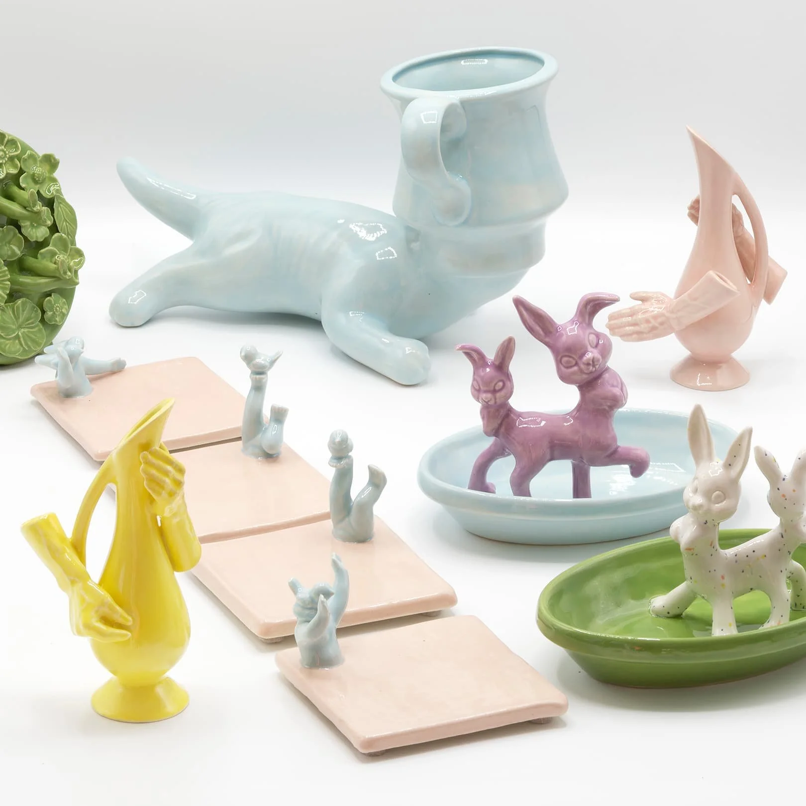 Collection of colorful ceramic animal sculptures, including rabbits, deer, and a whale, displayed on various pastel-colored trays and dishes.