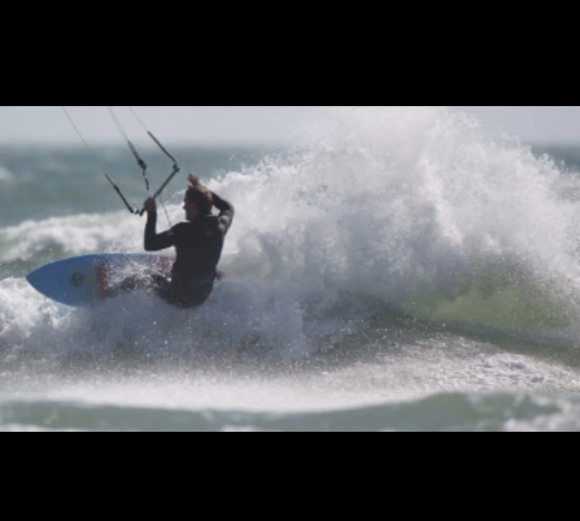 Kiteboarder riding a wave on the ocean.