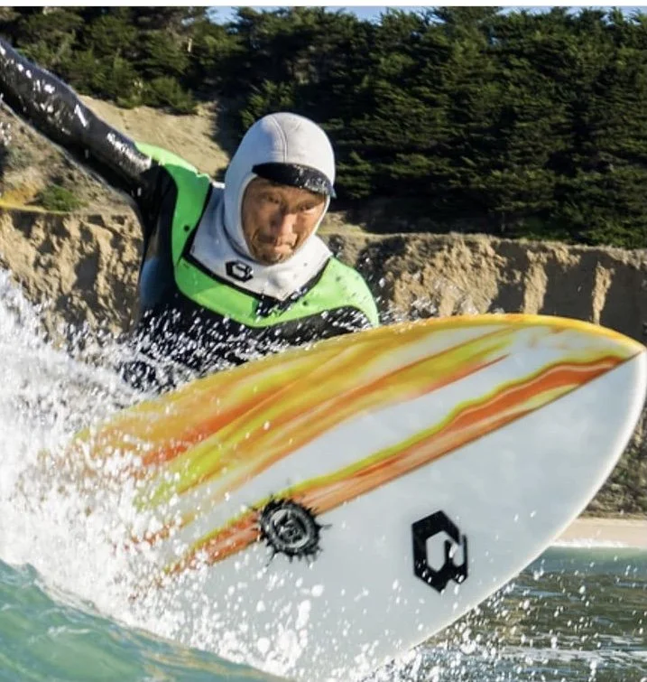 Surfer in protective gear riding a wave on a colorful surfboard
