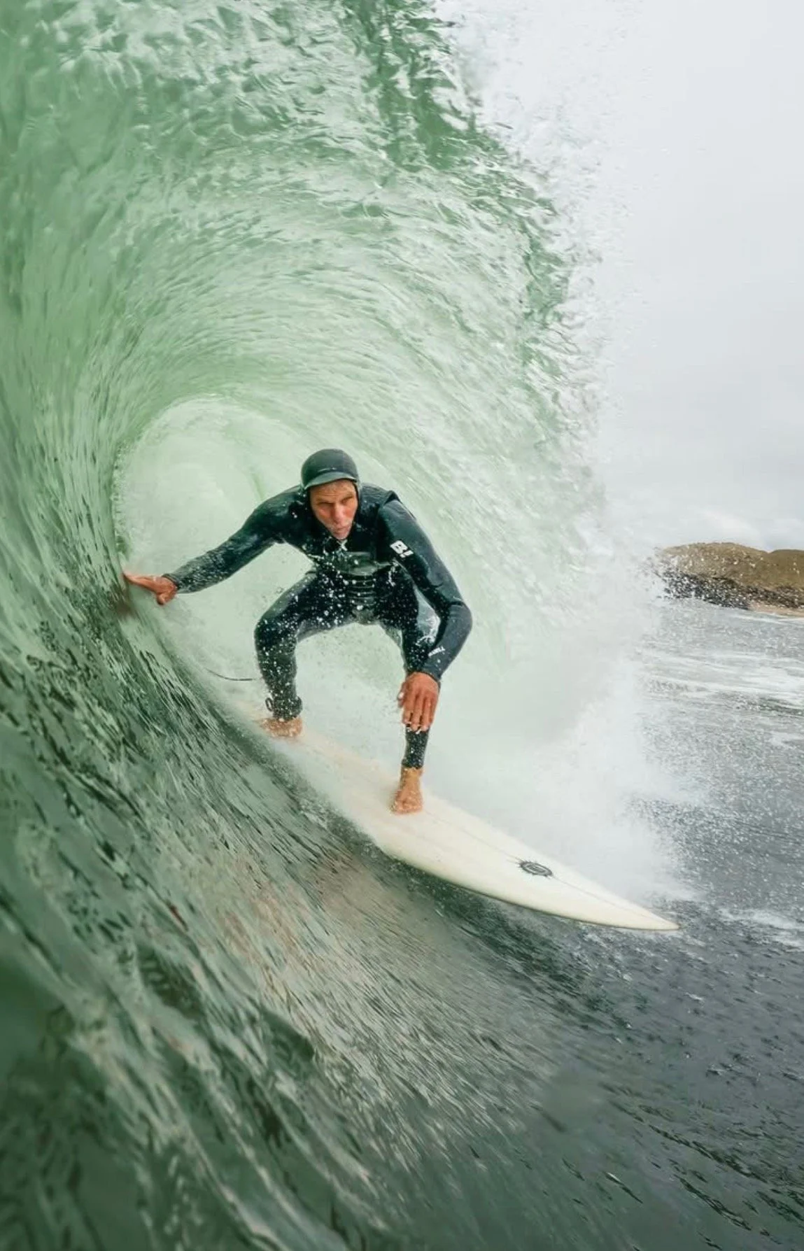 Surfer riding inside a large green wave.