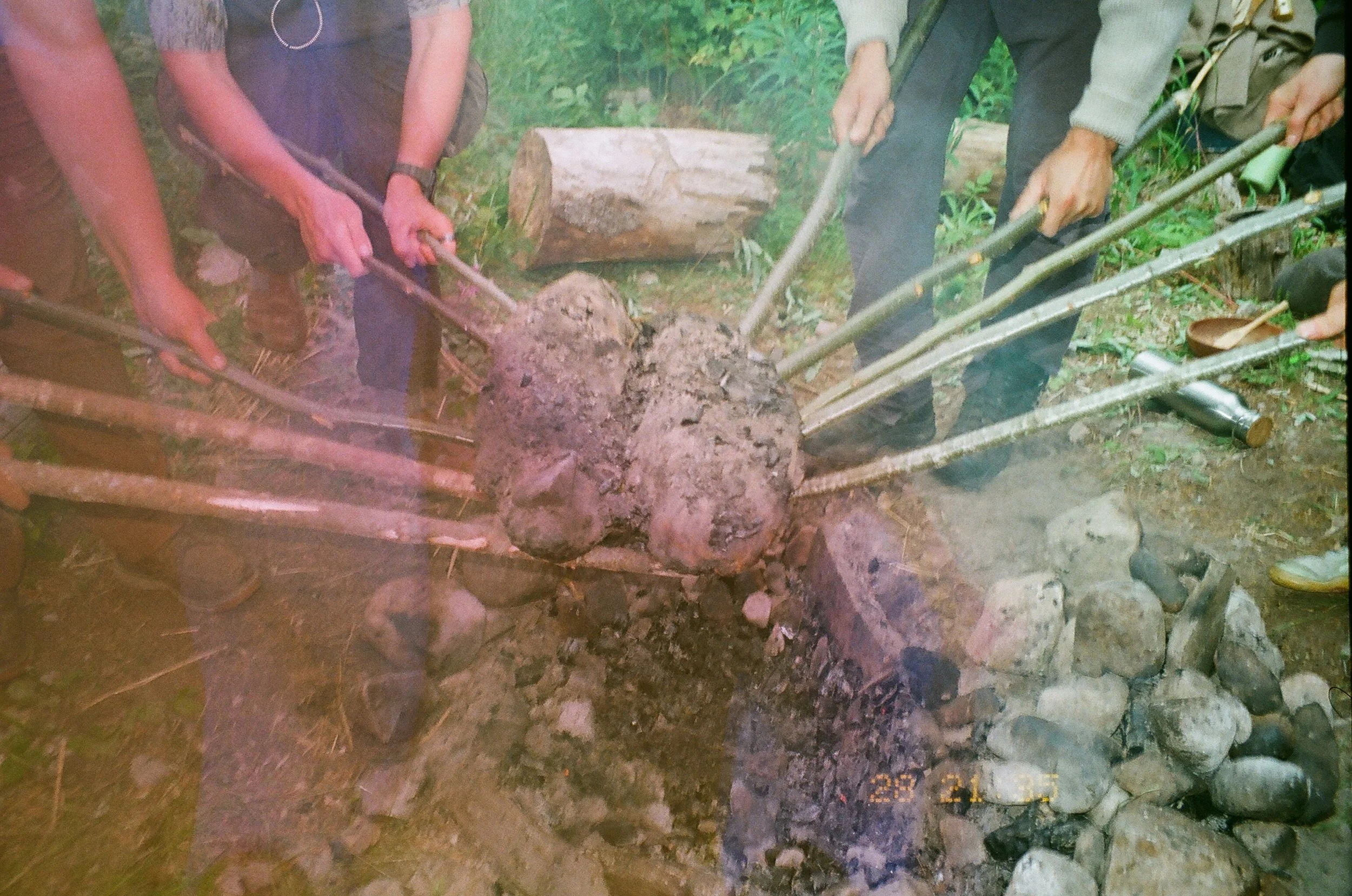 People chopping and moving logs in a forested area.