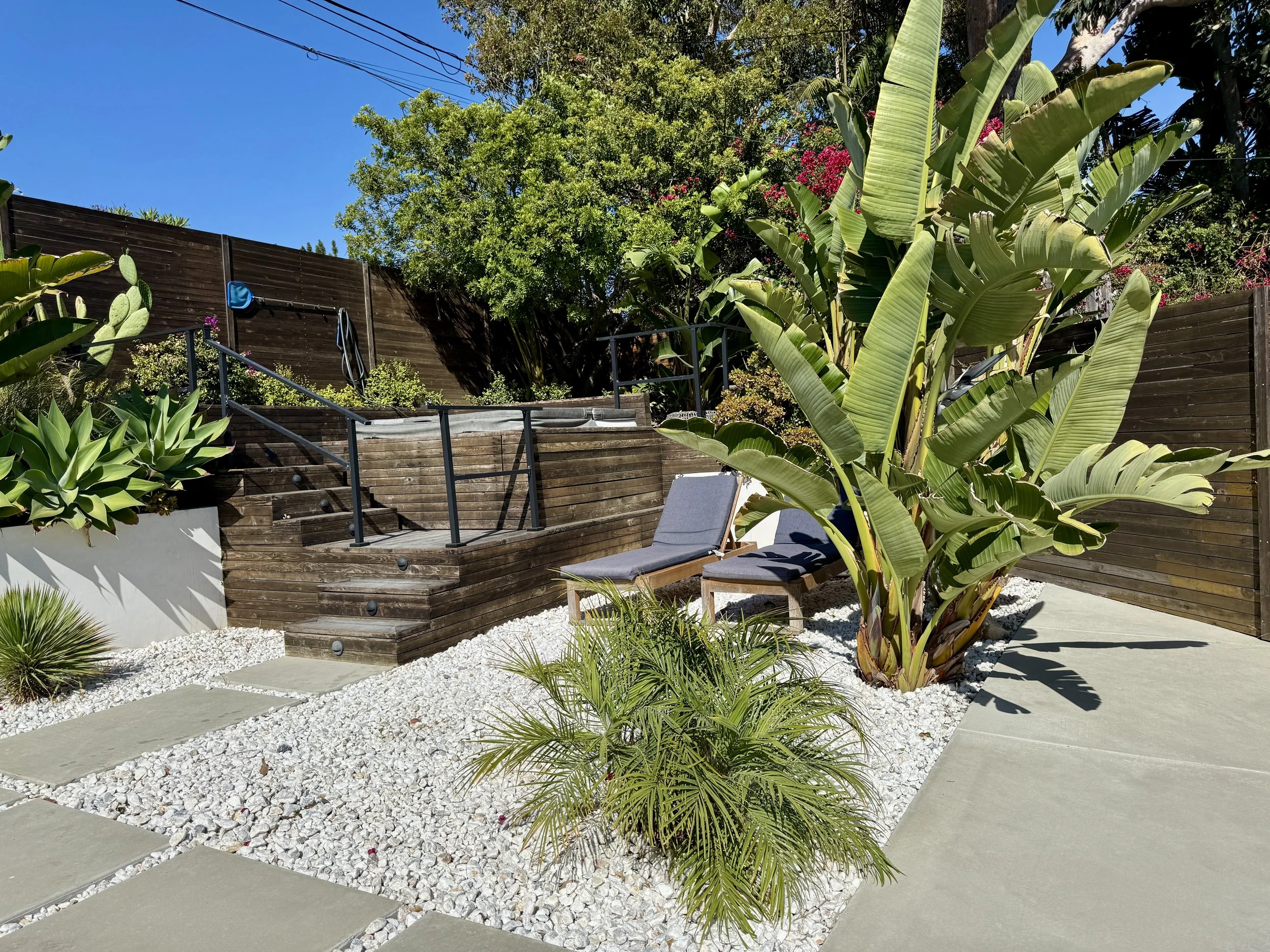 Built-in hot tub integrated into a modern wood deck with custom stairs, tropical planting, and contemporary landscape design in Malibu, CA.