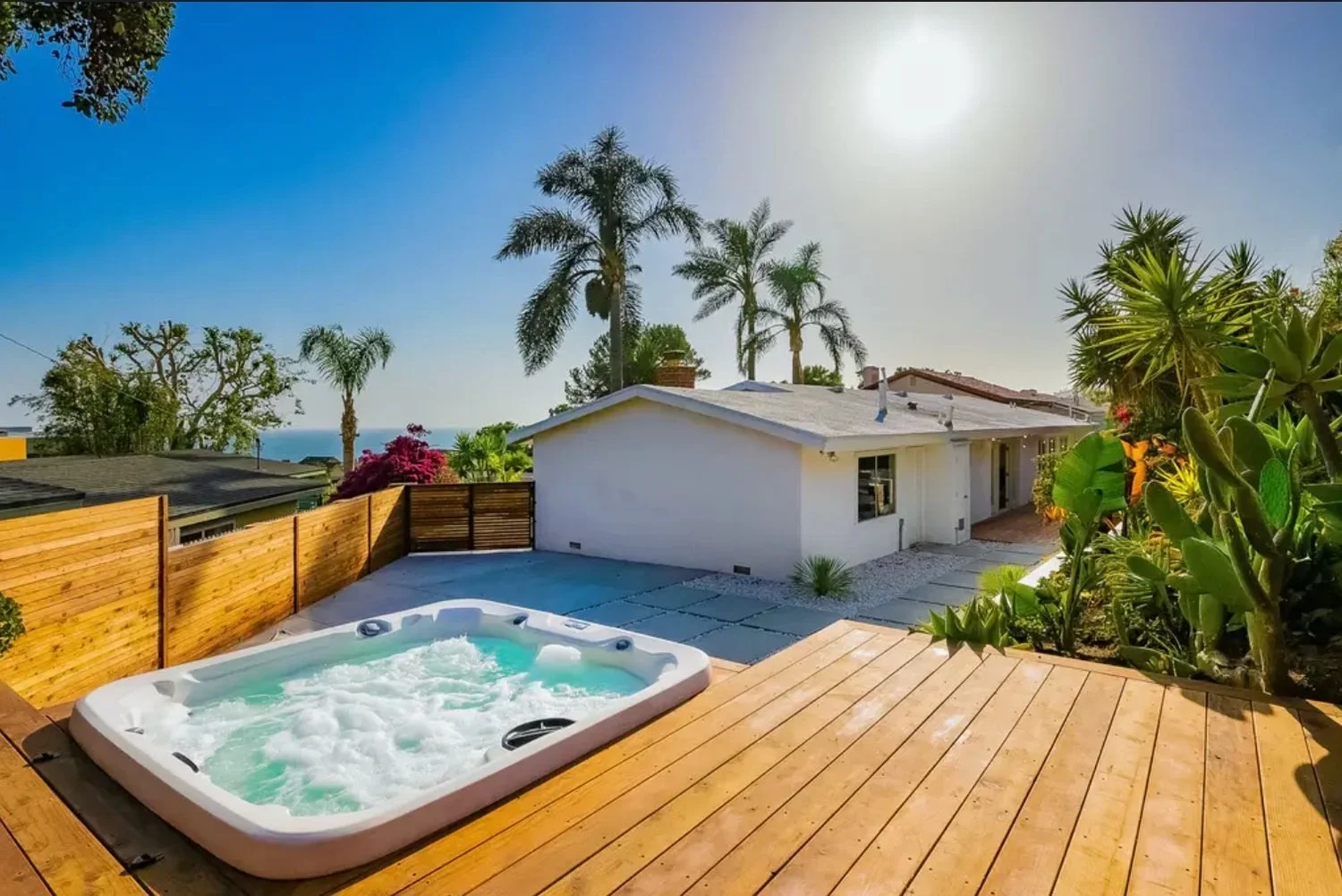 Modern Malibu backyard landscape featuring a hot tub, custom wood deck, tropical planting, ocean view, and contemporary outdoor living design.
