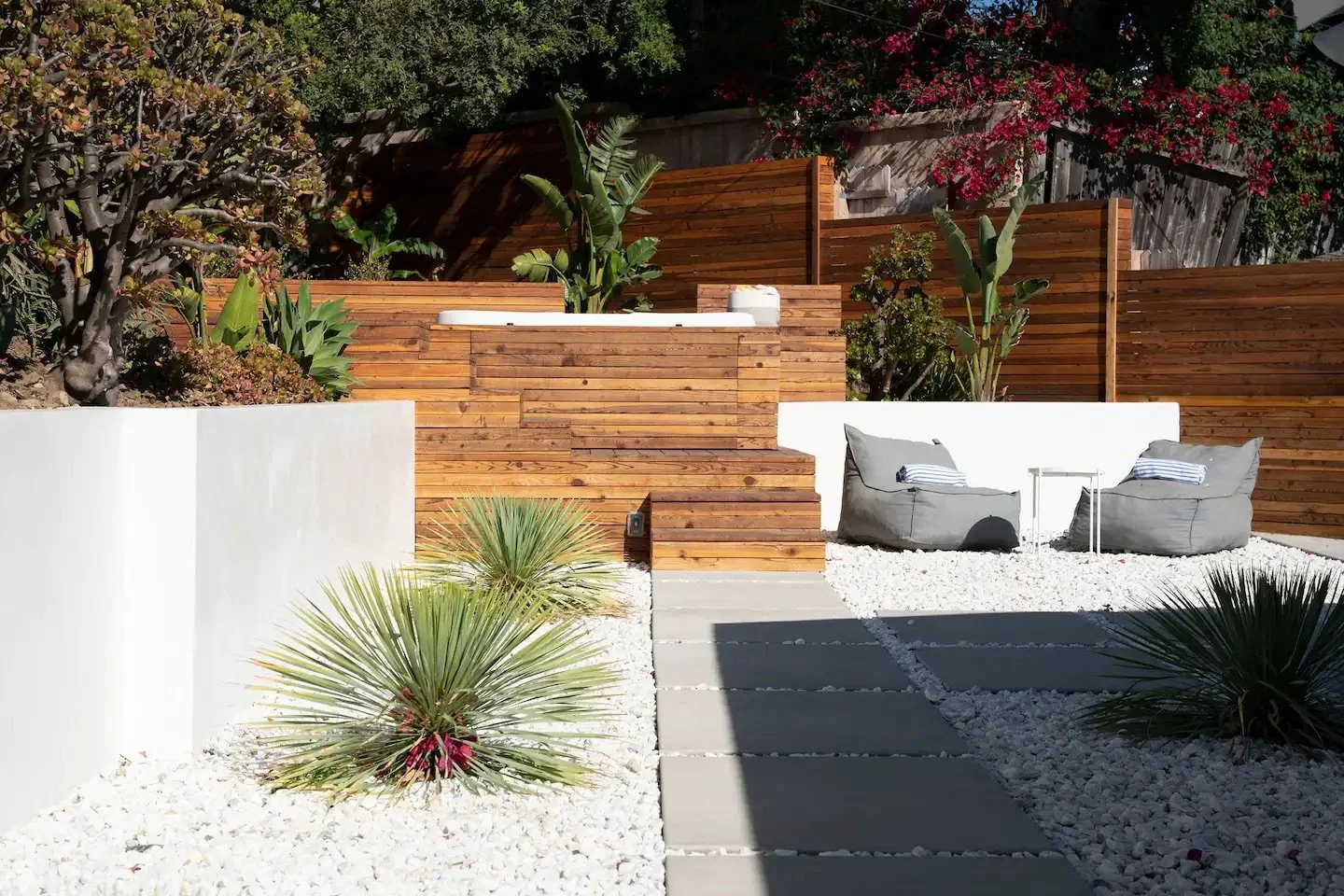 Built-in hot tub integrated into a custom wood deck with modern stairs, tropical planting, and contemporary backyard landscape design in Malibu, CA.