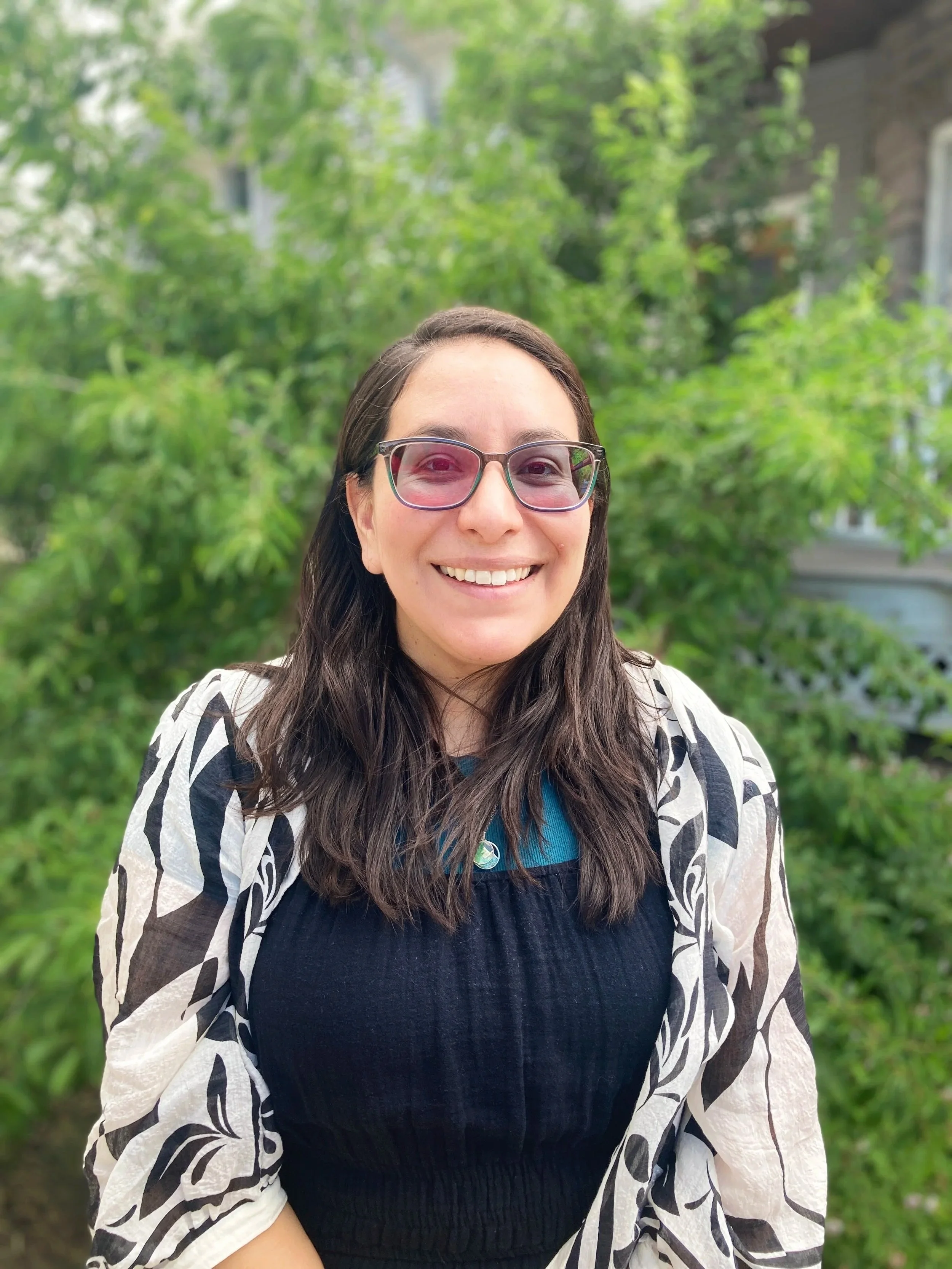 Latina woman with brown hair and glasses smiling