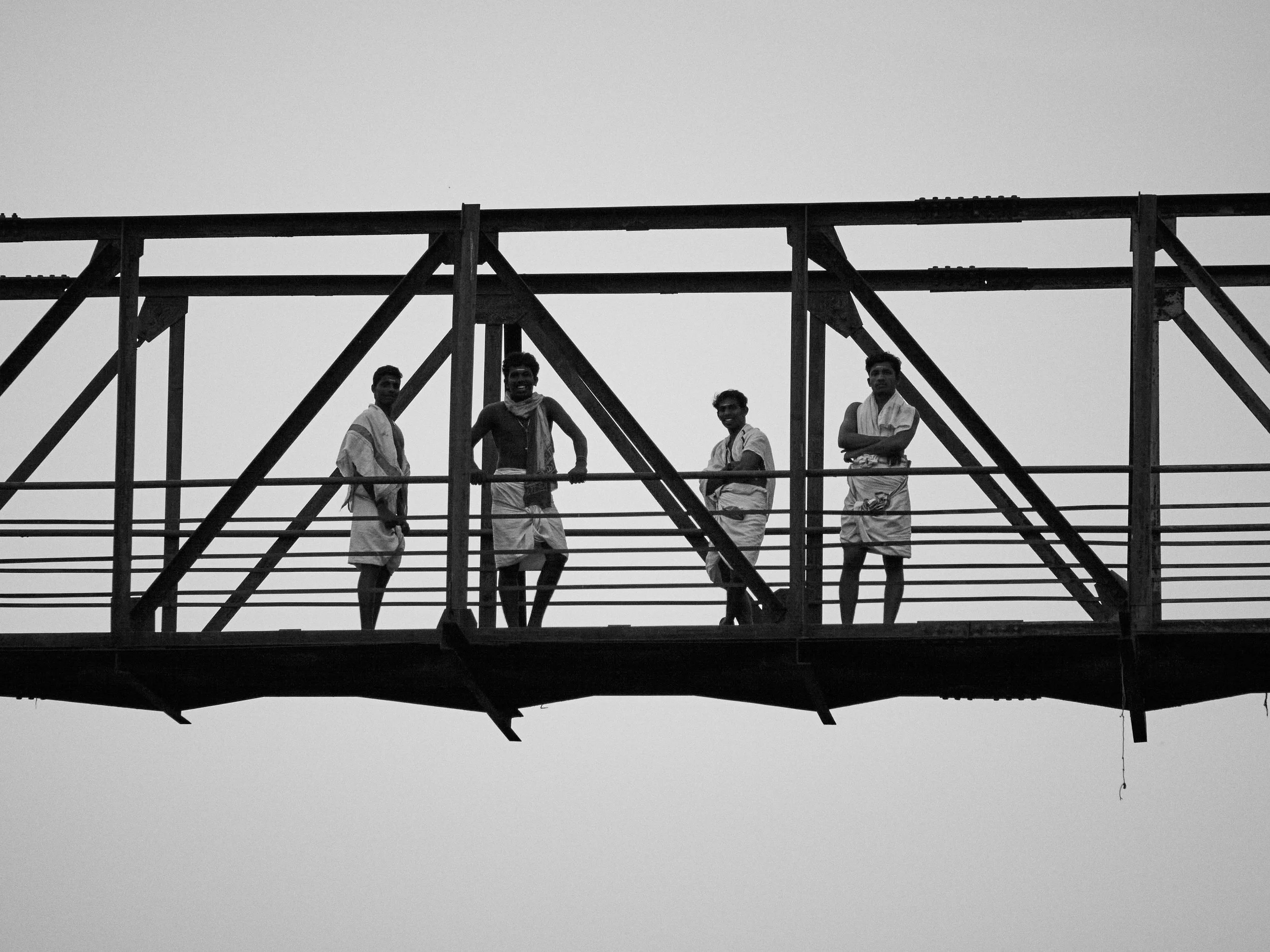 A group of young men dressed up in traditional cloth (veshti) standing over a bridge across the river in Alappuzha, Kerala.