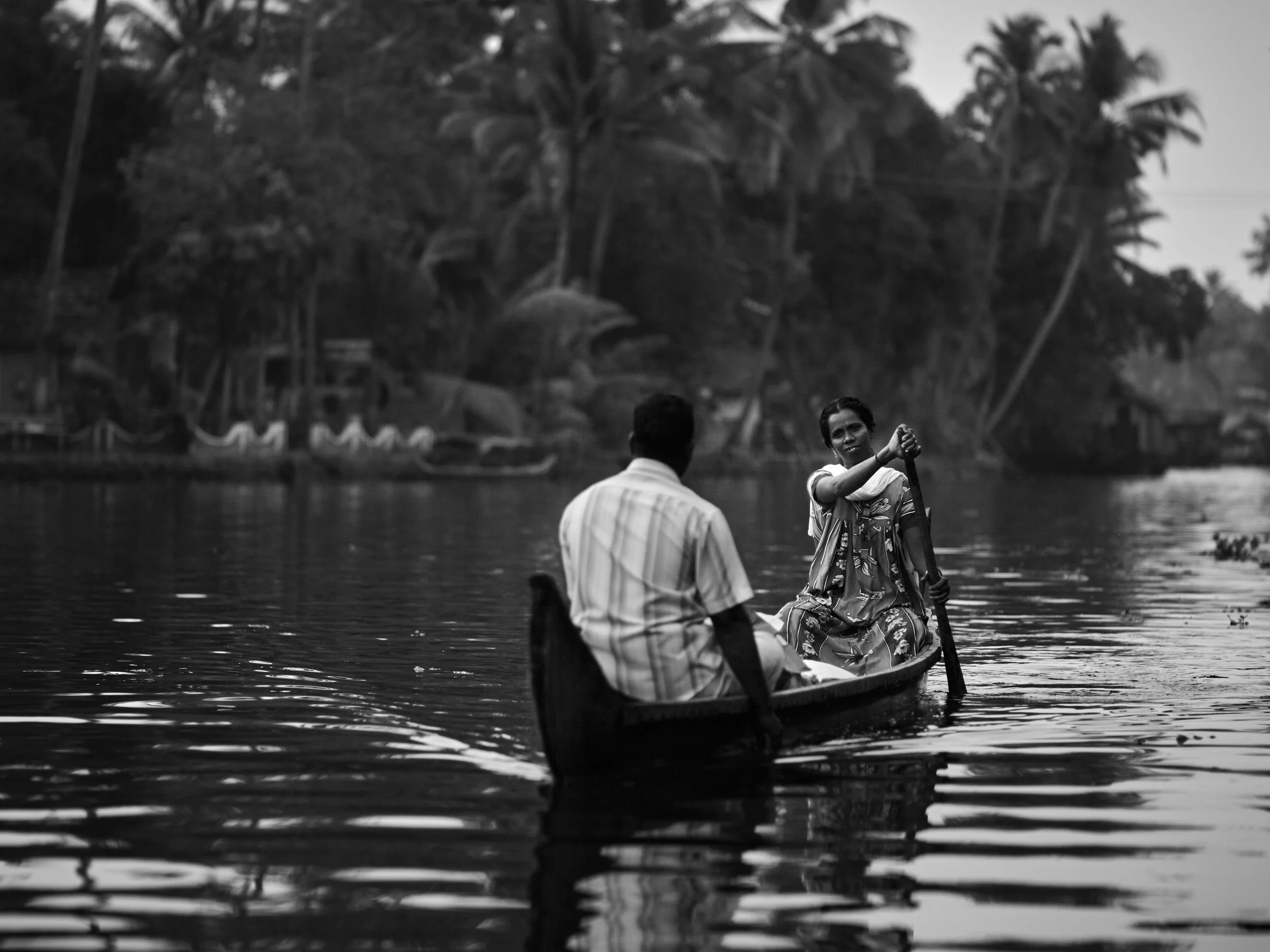A family using their small wooden boat to navigate around the winding water canal.