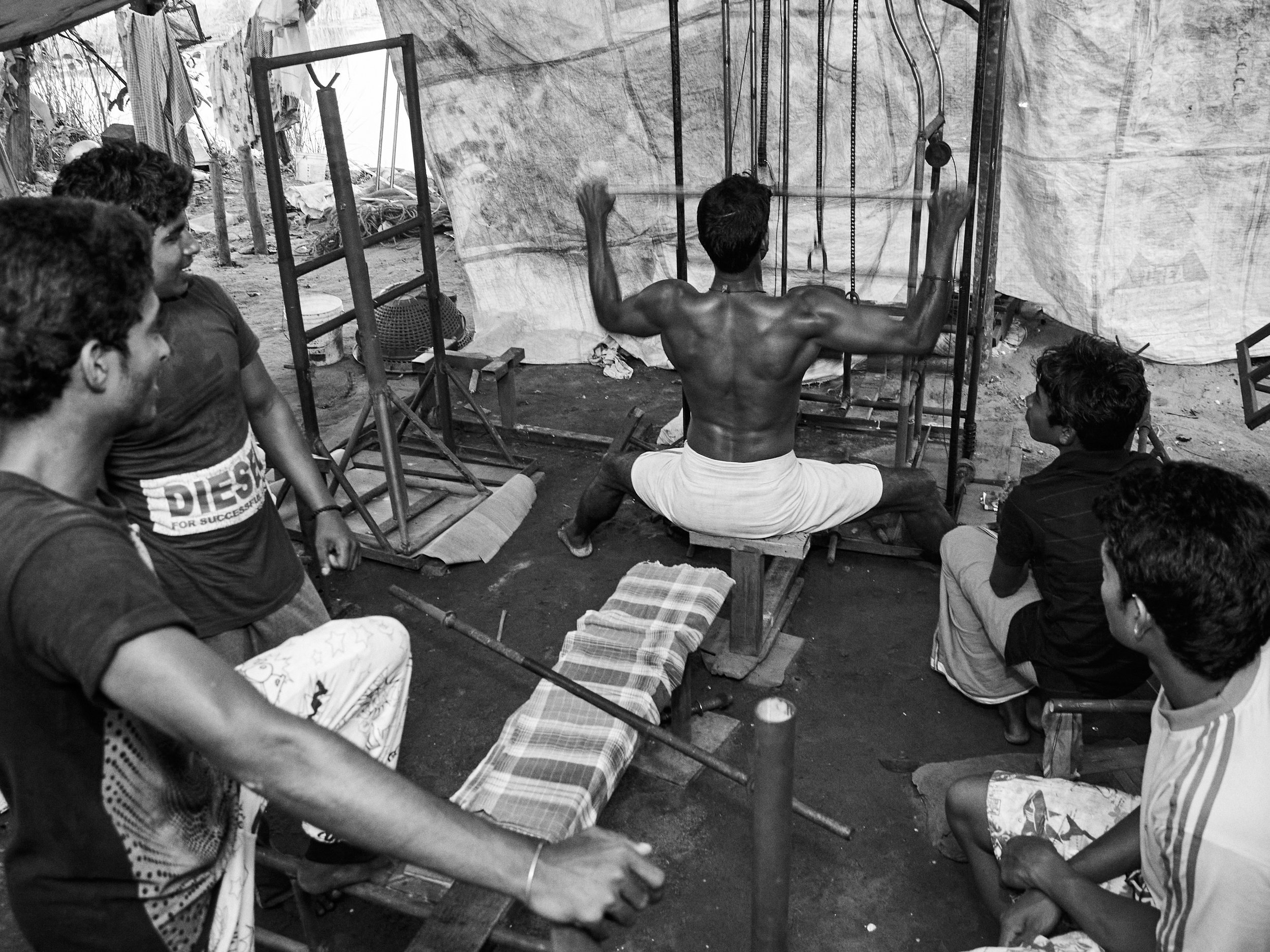 A group of young boys enjoying  enjoying weightlifting at a riverside makeshift gym.