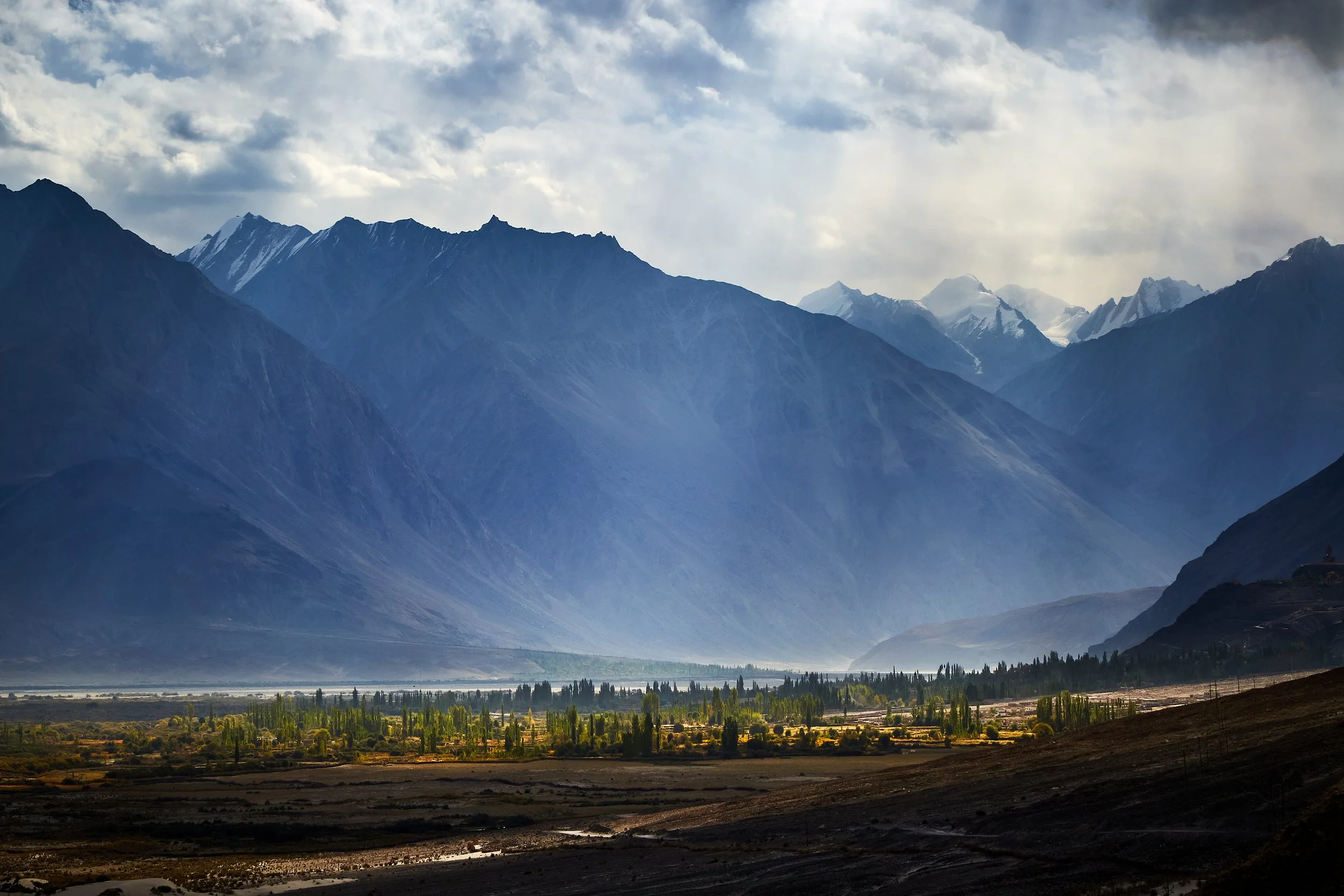 Sunlight penetrates through the dark clouds over Nubra valley. Ancient silk route between east and west crossed through the Karakoram mountain ranges in the vicinity.