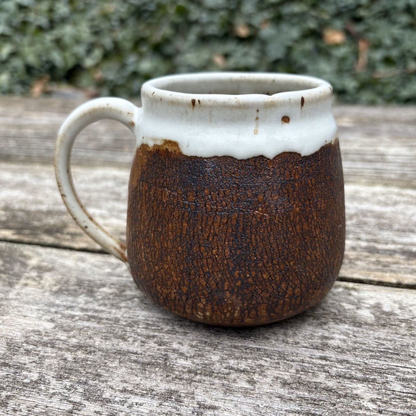 Right profile of mug, crackle textured exterior with thick satin white glazing on rim and handle.