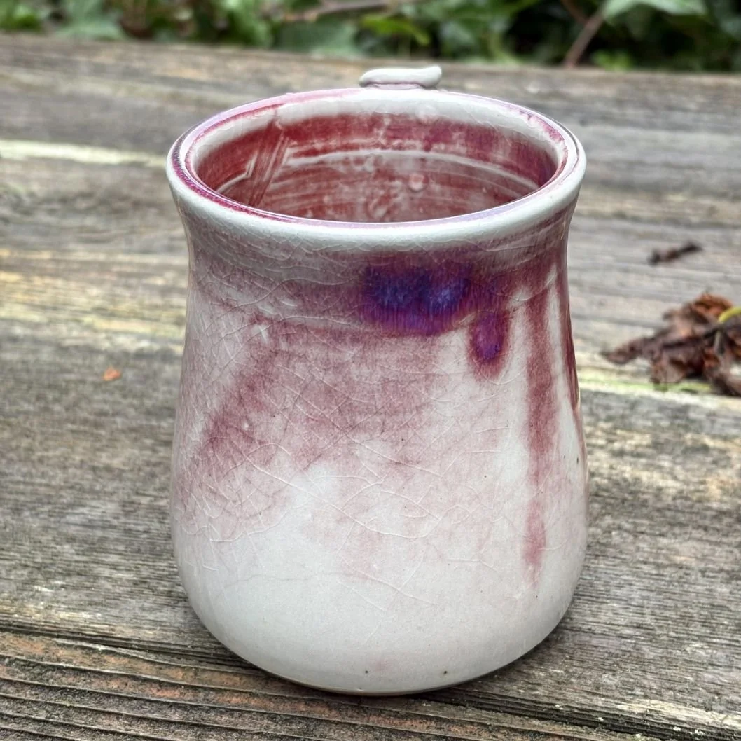 handmade ceramic mug with a deep wine-toned glaze fading into a pale greenish, lightly crackled base and a rounded pulled handle