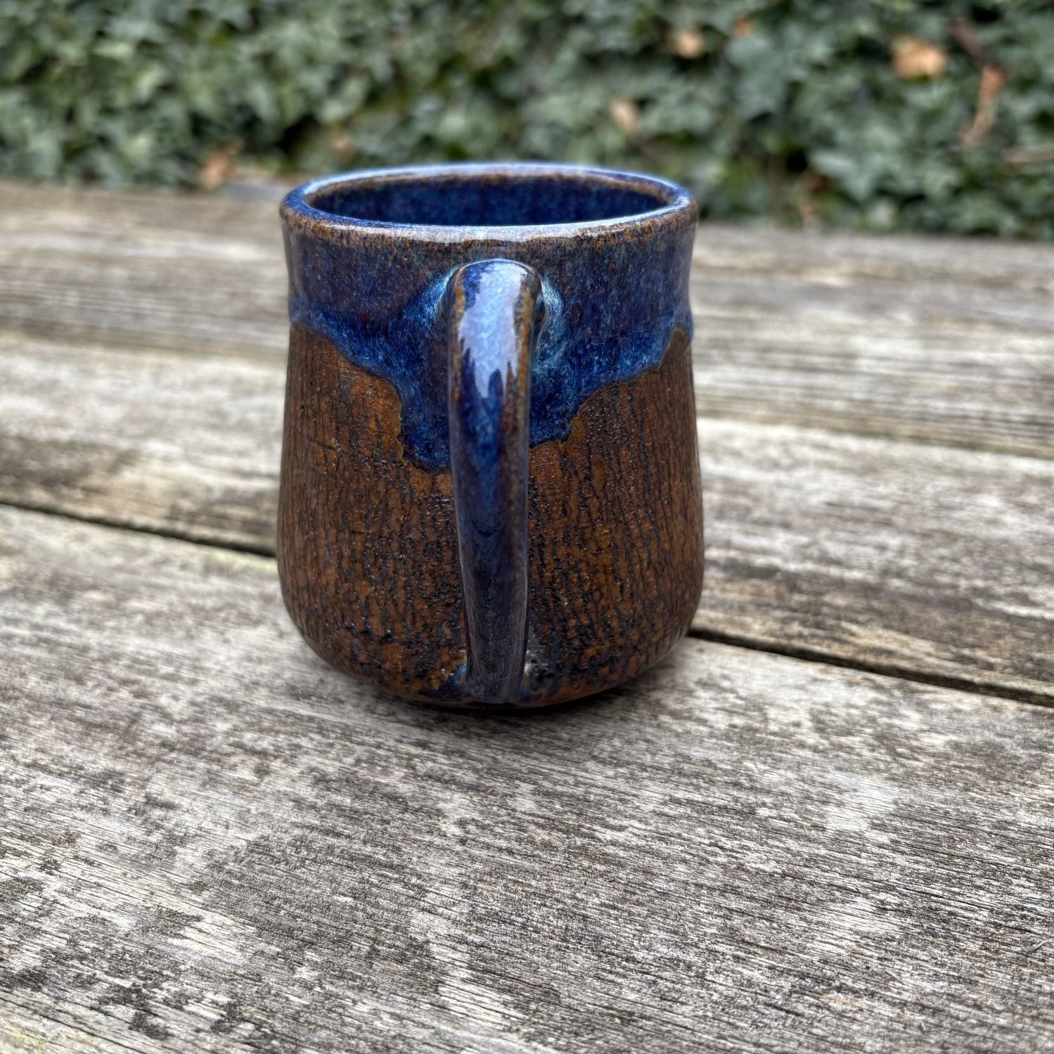 Rear profile of mug, crackle textured exterior with deep blue rutile glazing on rim and handle centered..