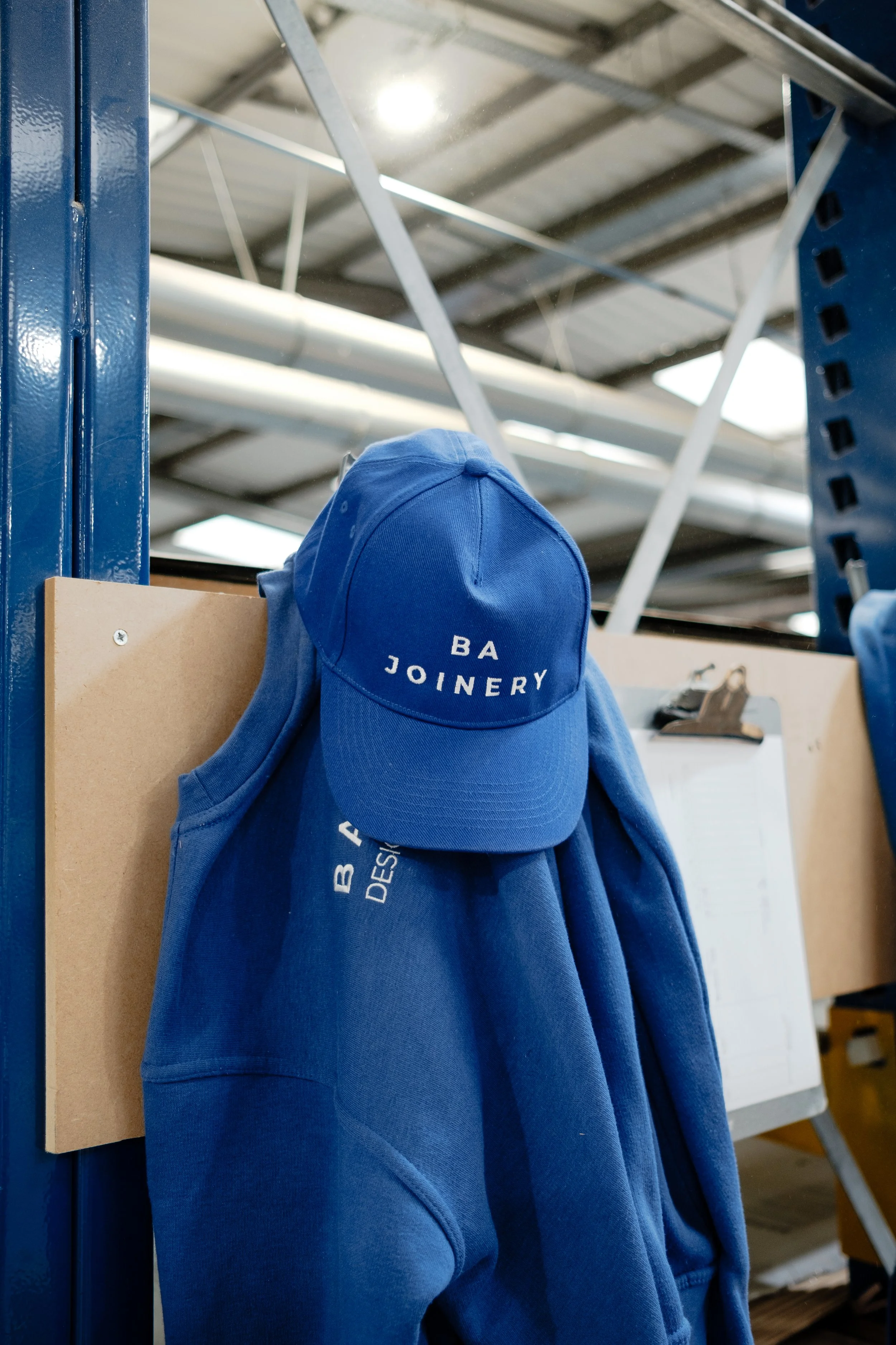 Blue baseball cap and blue hoodie hanging on hooks in a storage area or workshop.