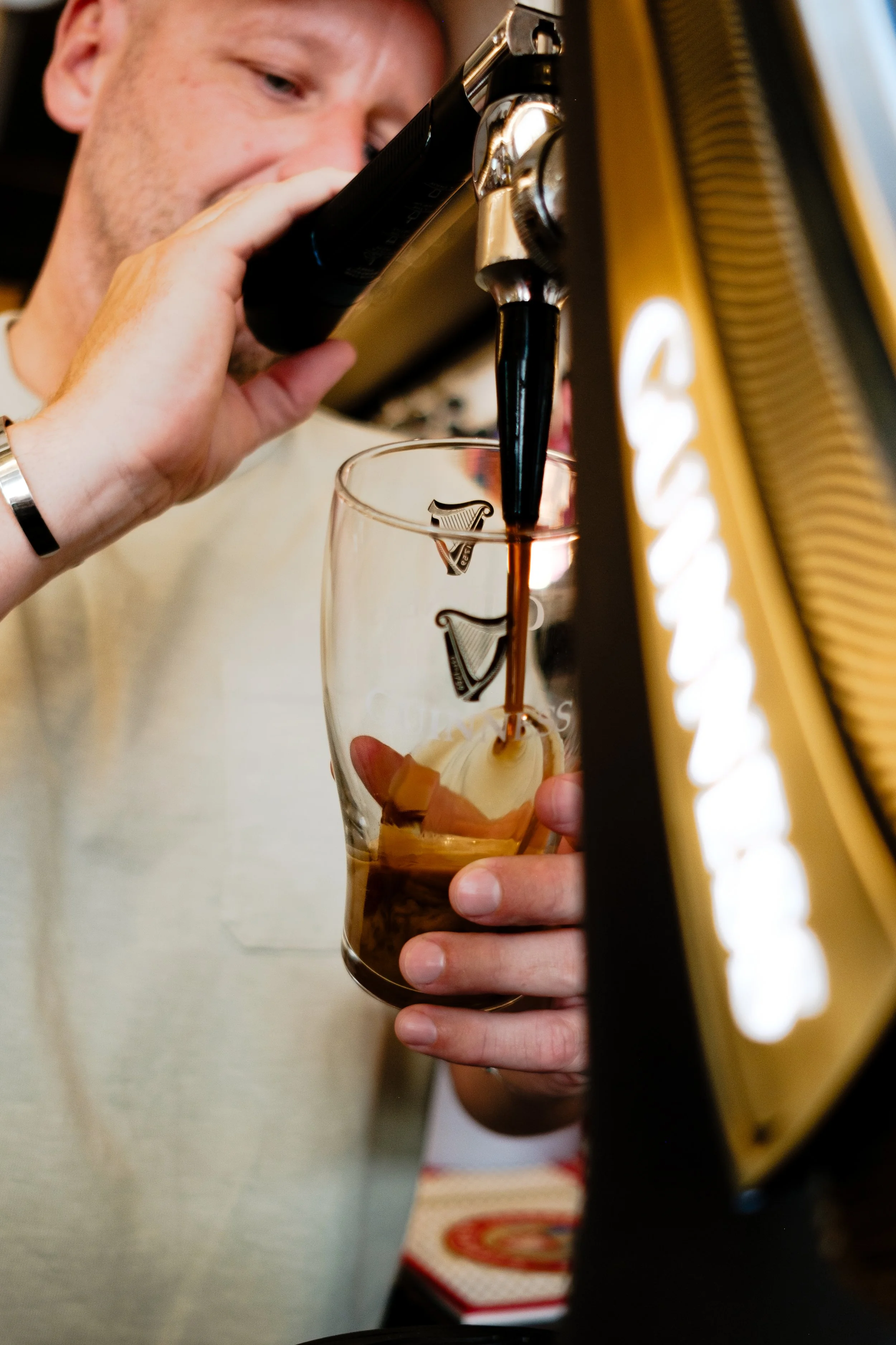 Man pouring draft Guinness stout into a glass at a bar.