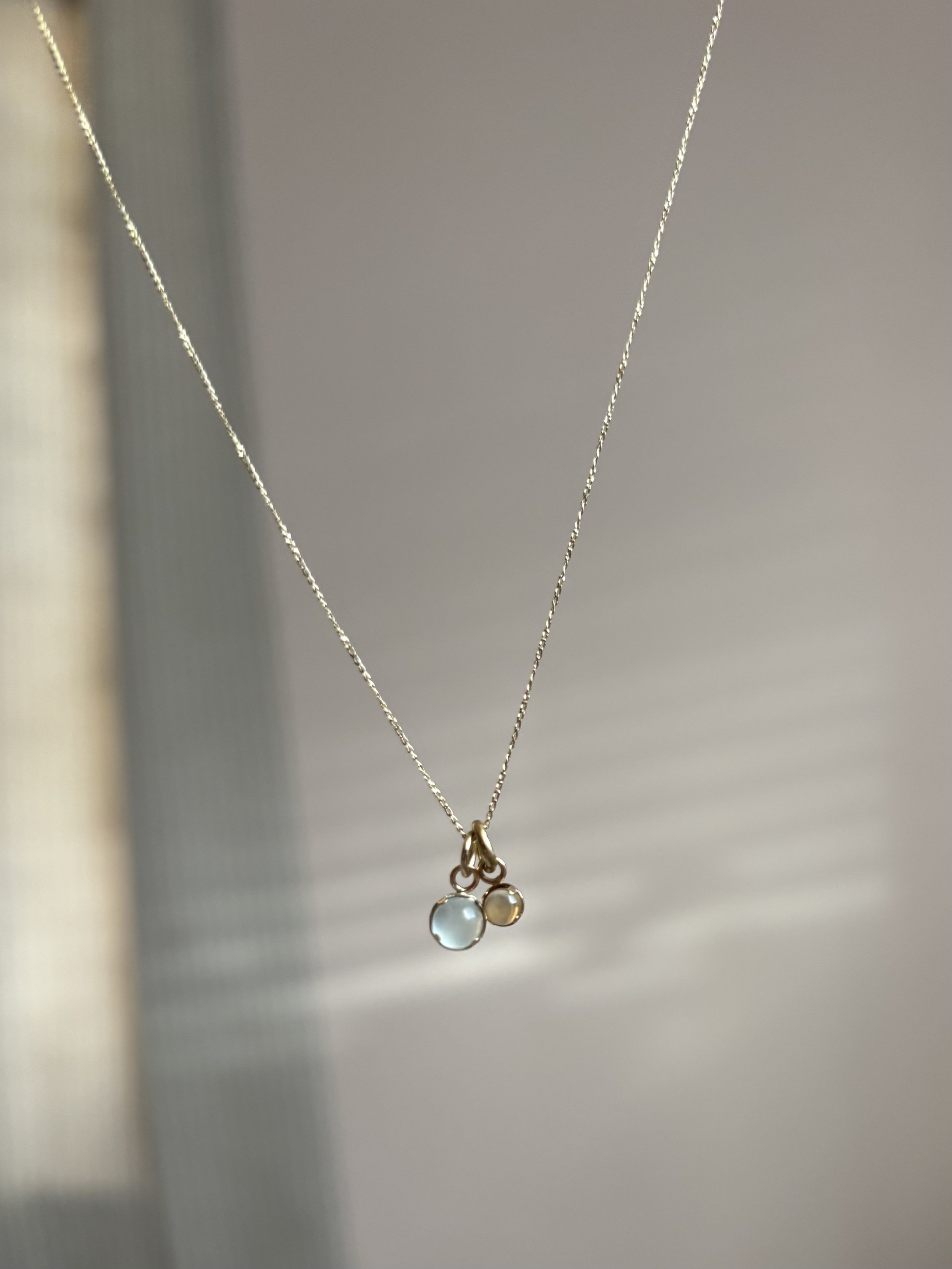 A delicate necklace with three small round pendants hanging from it, two of which appear to be gemstones.