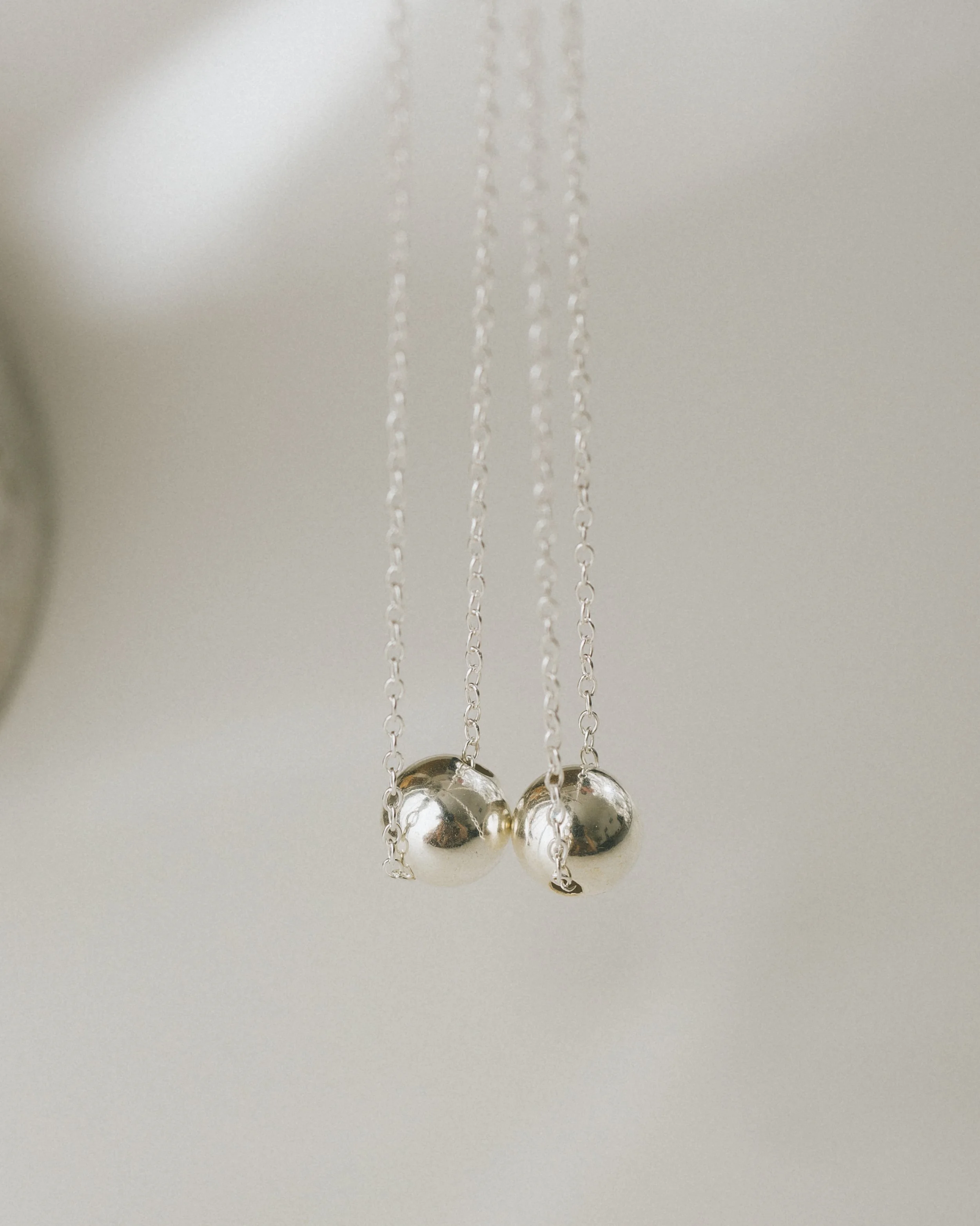 Silver necklace with three spherical pendants hanging from three delicate chains.