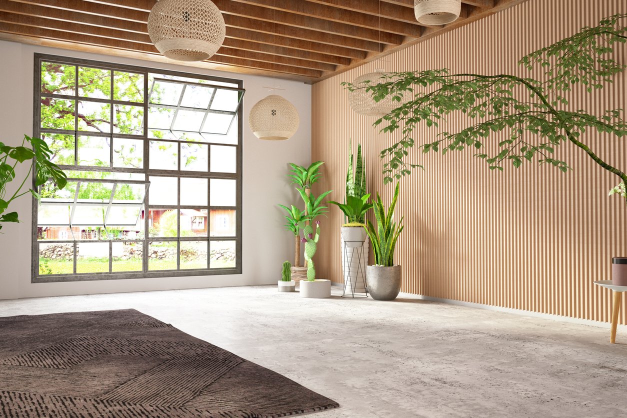 Modern indoor room with large window, wooden ceiling beams, hanging woven pendant lights, potted plants, and a textured rug.