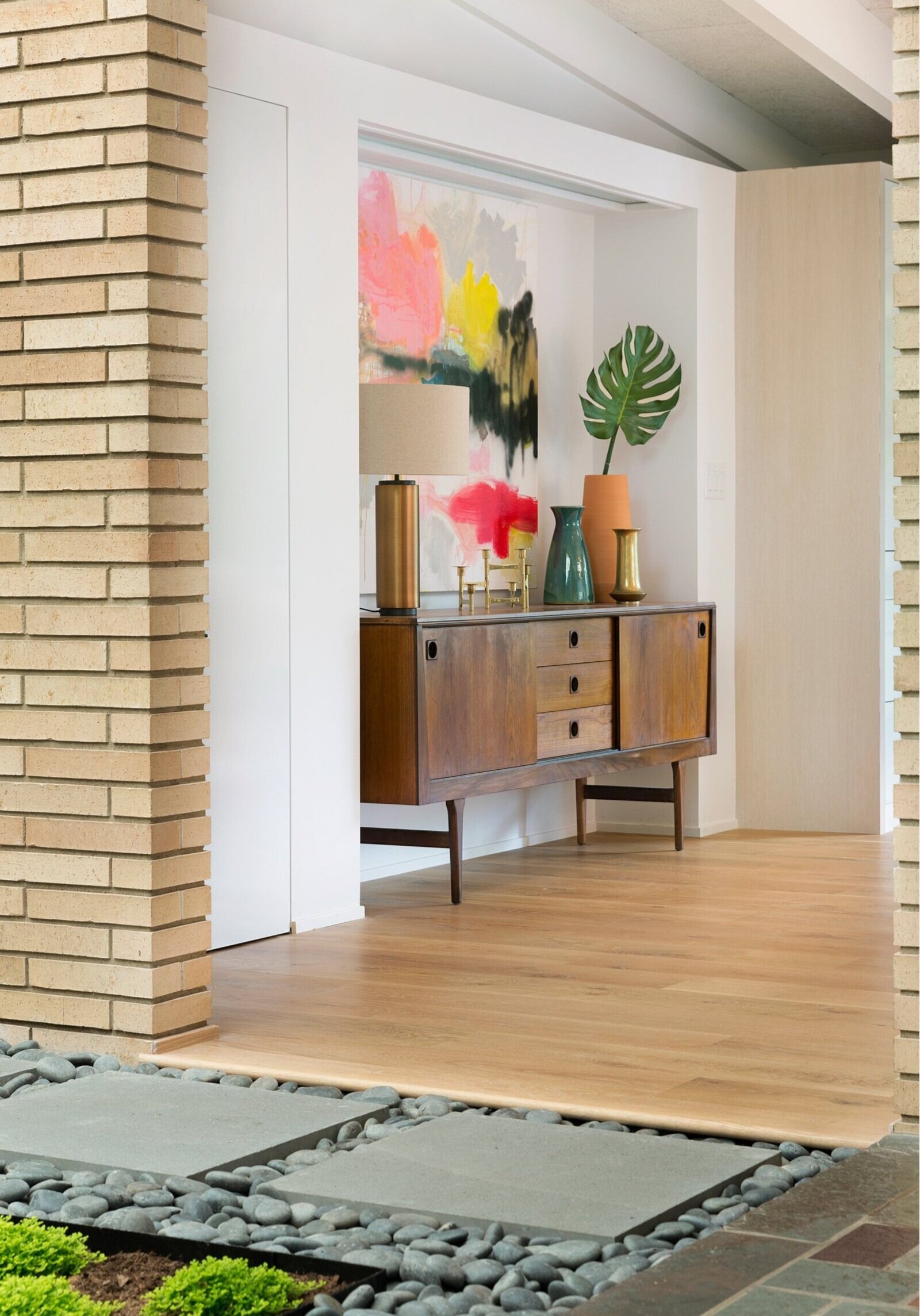 Home entryway with large vibrant artwork, multiple vases and greenery