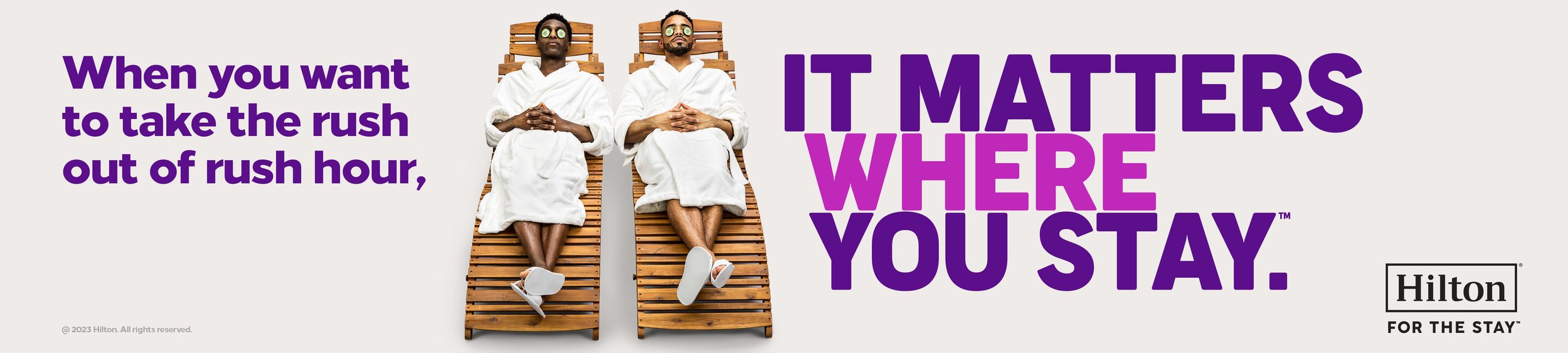 Two men in white bathrobes and sunglasses lying on lounge chairs and relaxing in a spa setting, with text promoting Hilton for stays during rush hour.