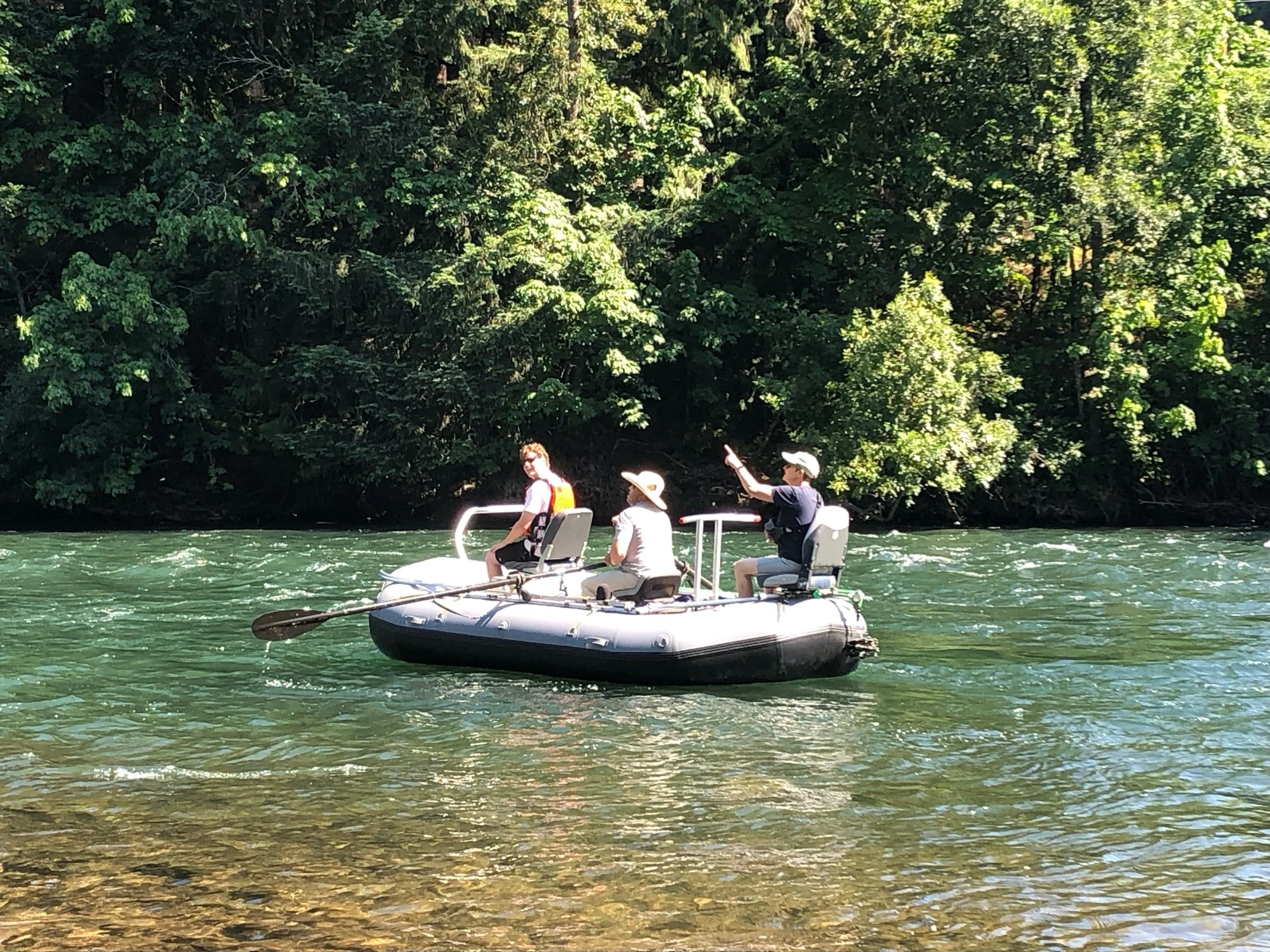 Group of people in raft on clear river surrounded by trees