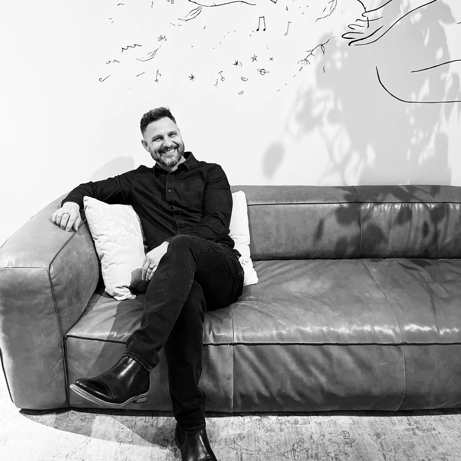 edmonton counsellor craig wanless sitting on a couch looking relaxed in black & white