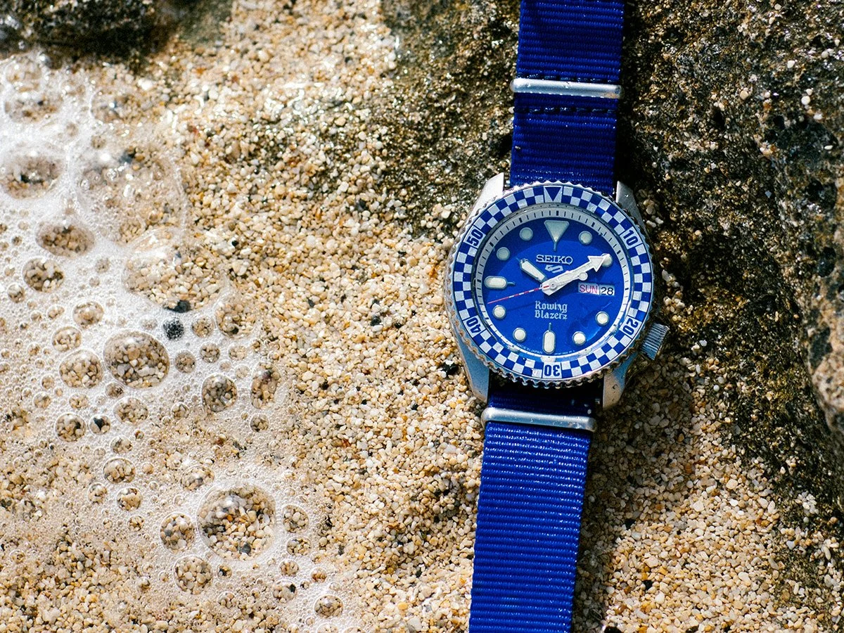 Seiko x Rowing Blazers racing watch detail in sand with ocean bubbles, photography by Daeja Fallas for GQ