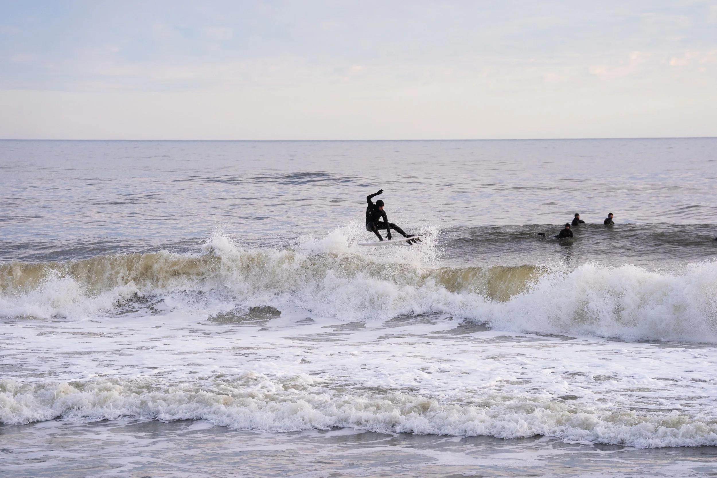 Surfer in atlantic ocean chucking air infront of the boys