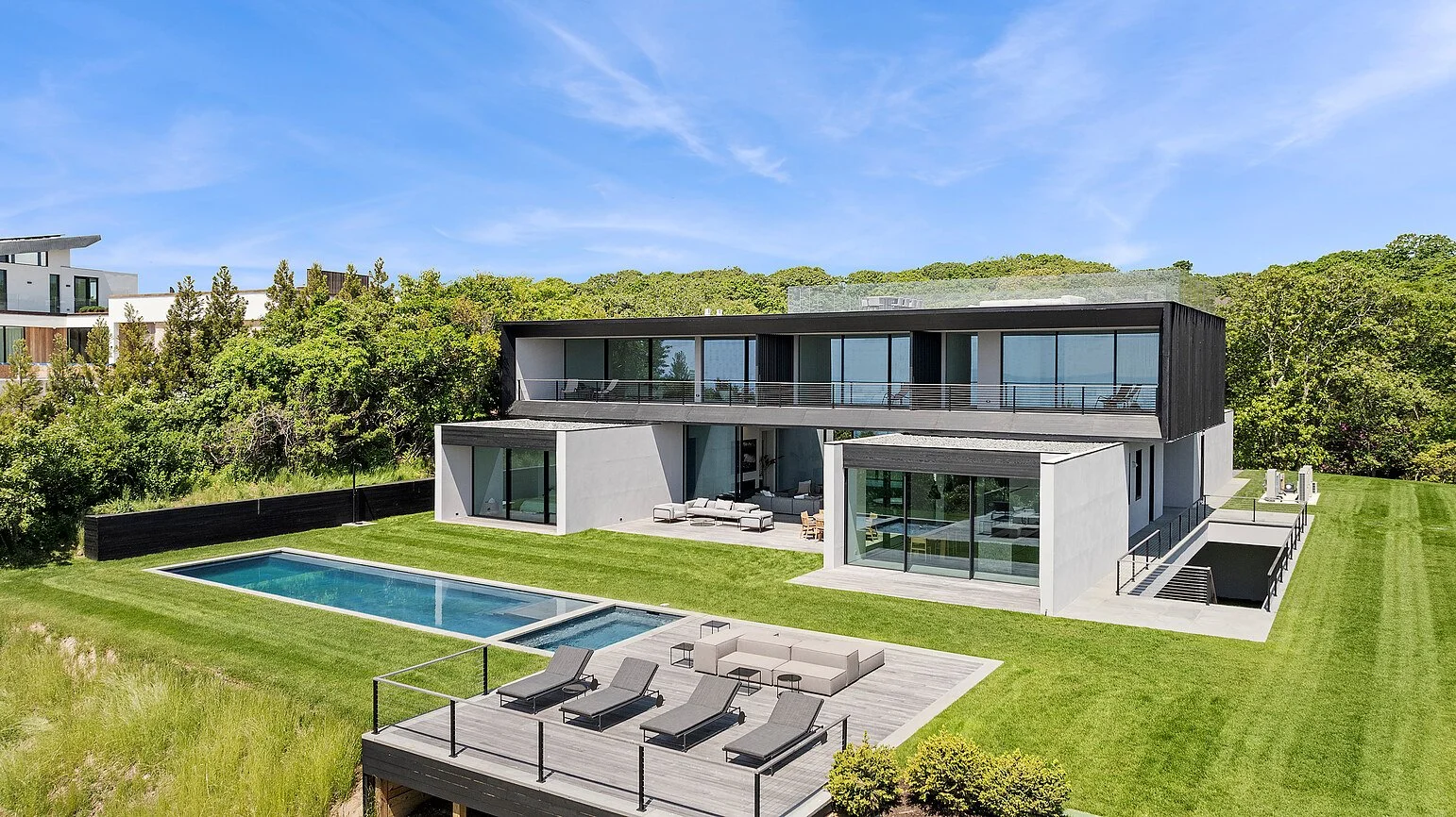Aerial view of a modern Hamptons home with pool, sun deck, and rooftop terrace