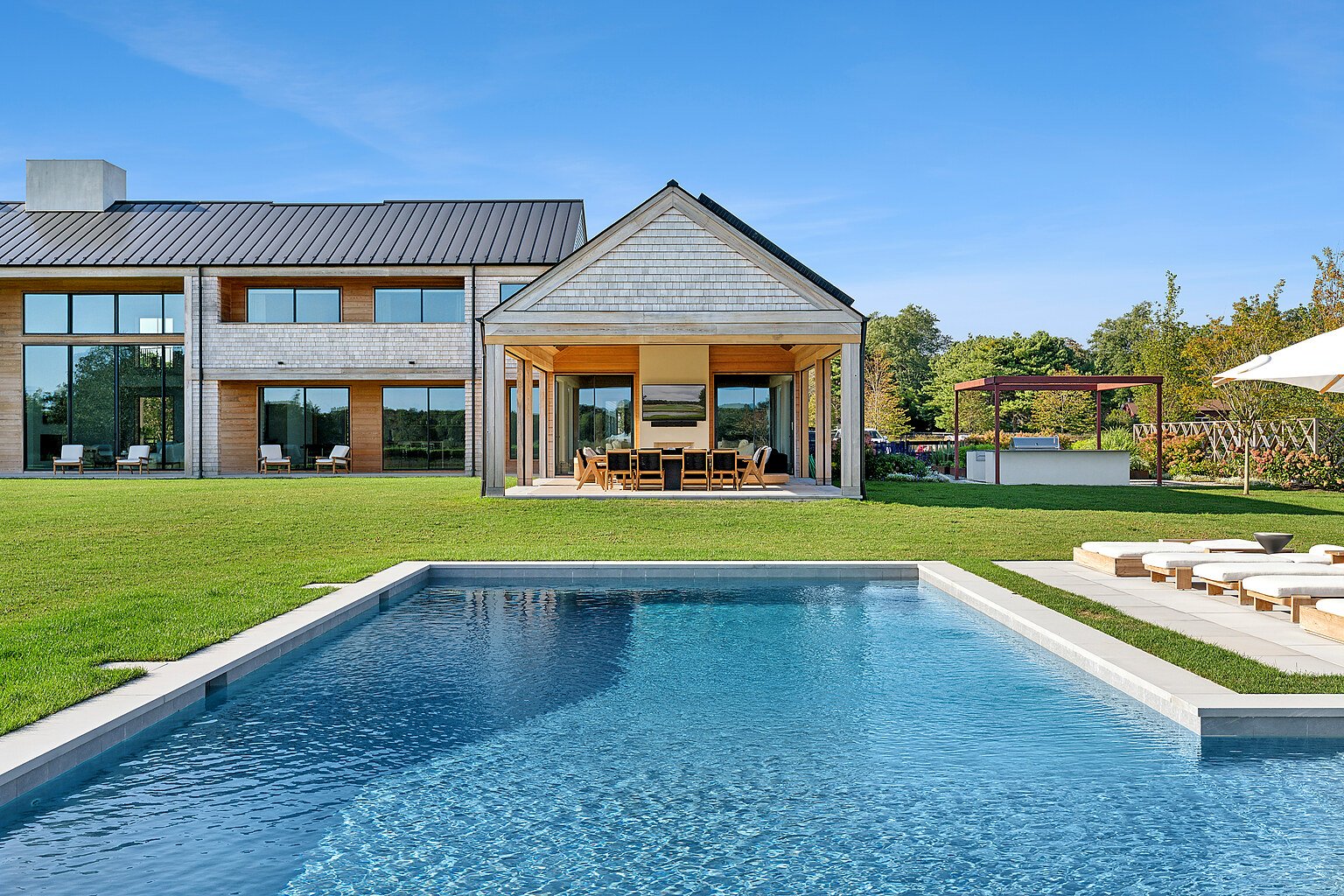 Backyard pool and covered outdoor lounge at a modern Hamptons home