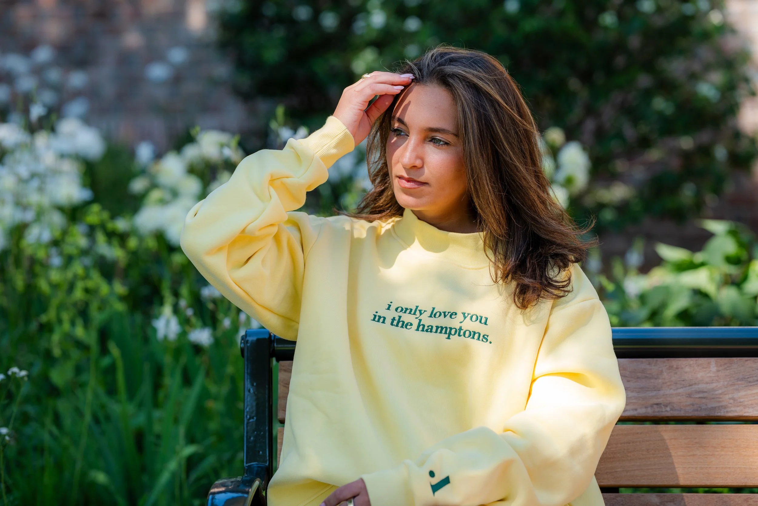 Personal branding portrait of a woman on a garden bench in the Hamptons