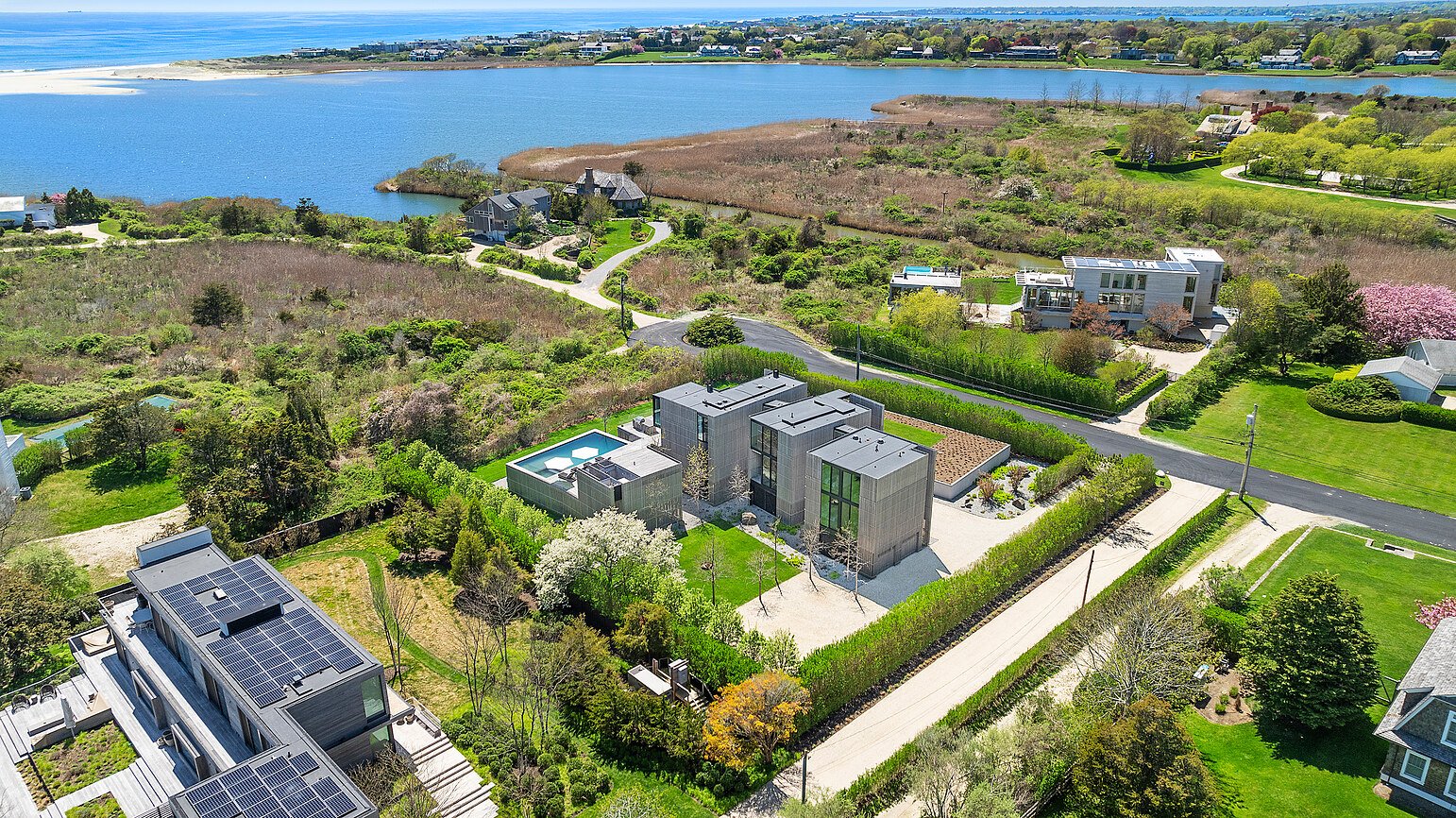High aerial view of a Hamptons neighborhood with the bay and ocean beach beyond