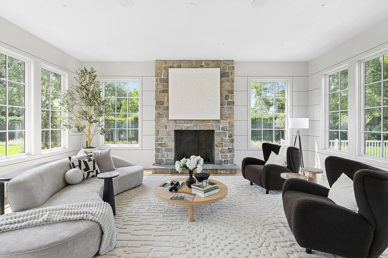 Staged living room with a stone fireplace and white shiplap walls in a Hamptons home