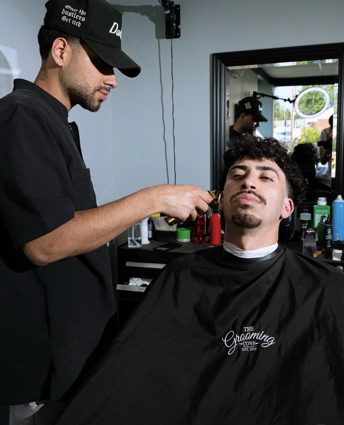 Barber cutting a client's curly hair at The Grooming Cove