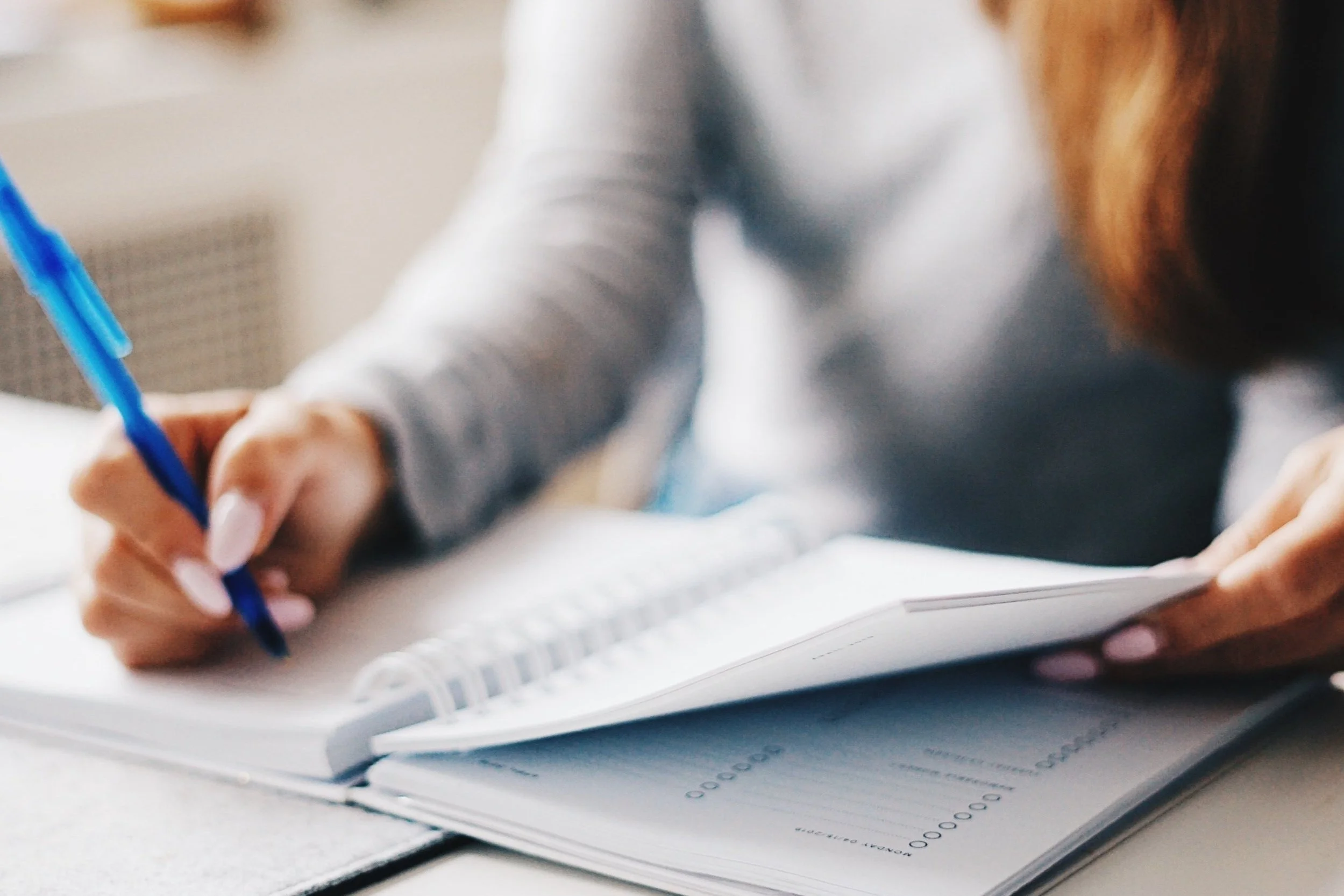 Woman writing down notes in her planner to stay organized.